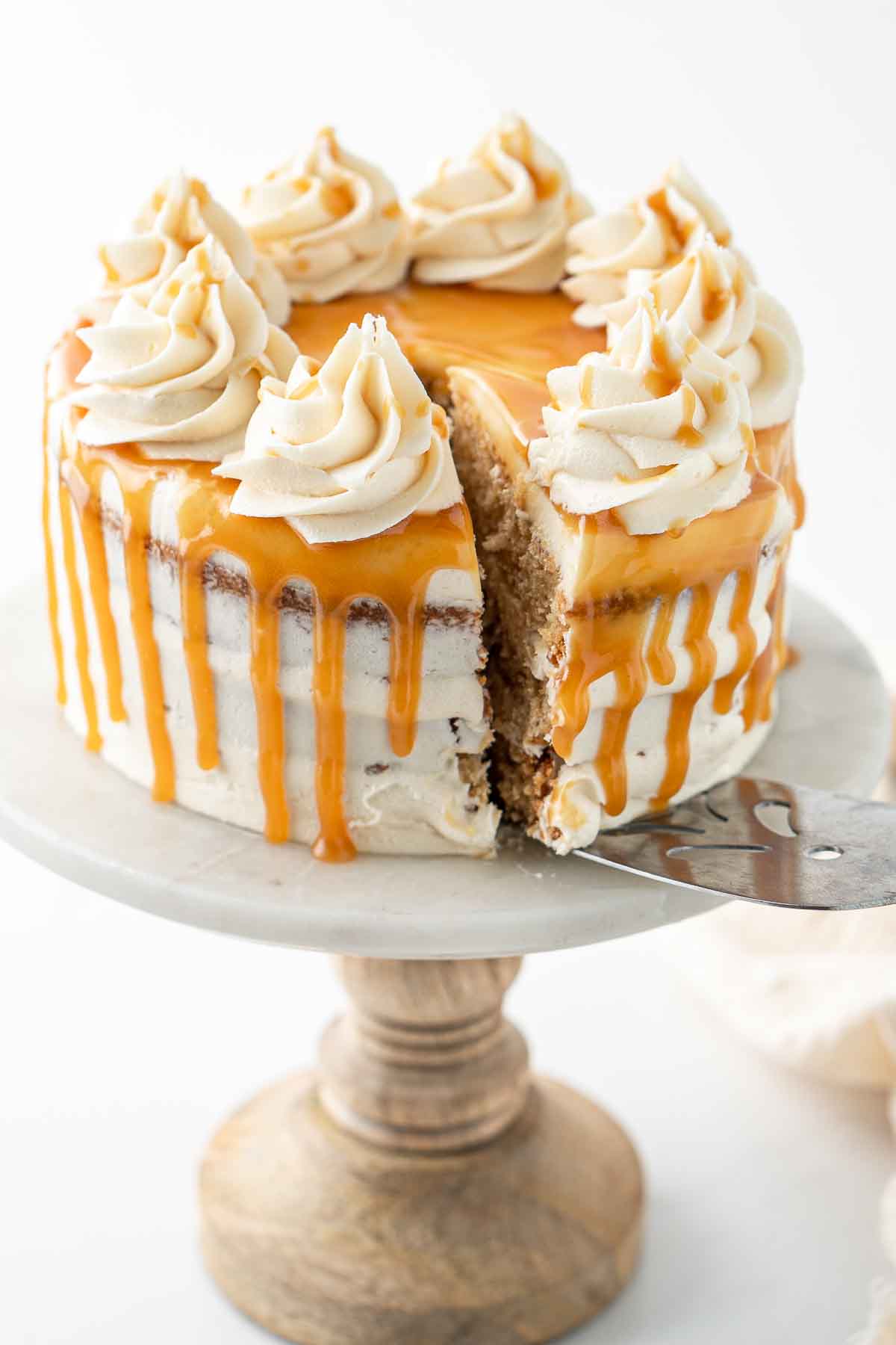 A slice of caramel cake being served from the cake stand.