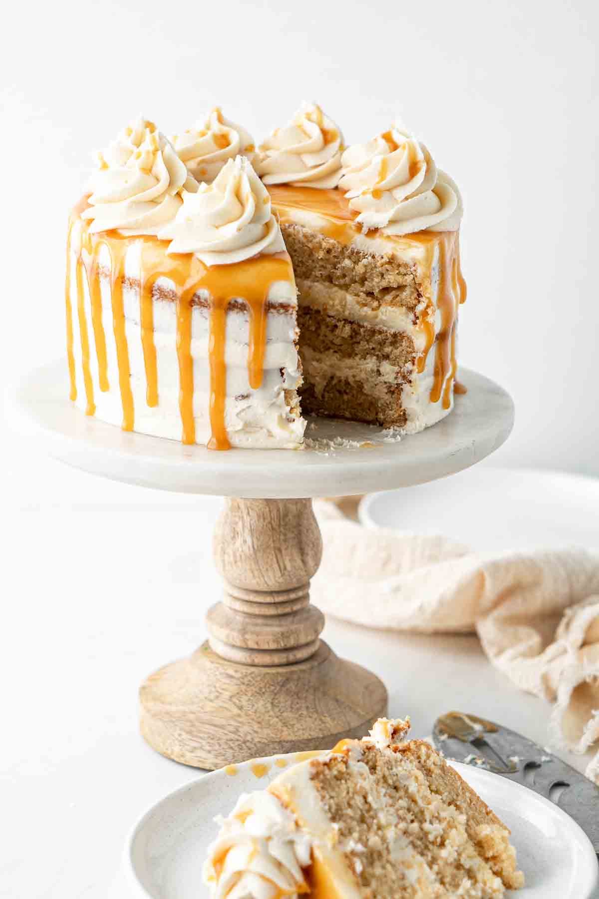 Vegan caramel cake on a cake stand with a slice cut.
