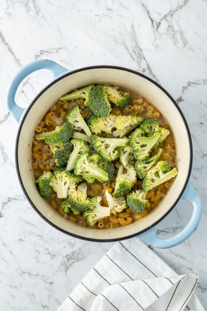 Adding the broccoli to the pot of pasta.