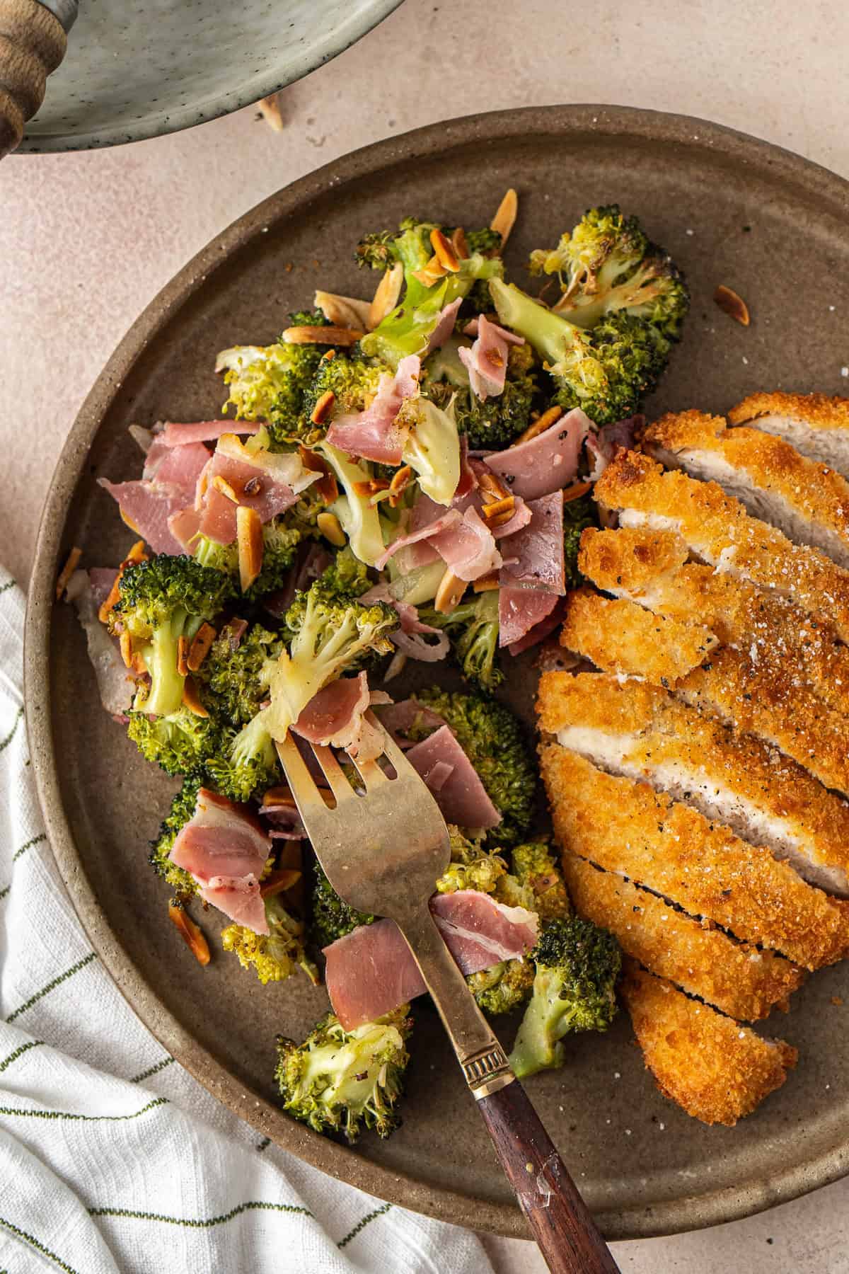 Close up of a fork taking a bite of the salad from a plate.