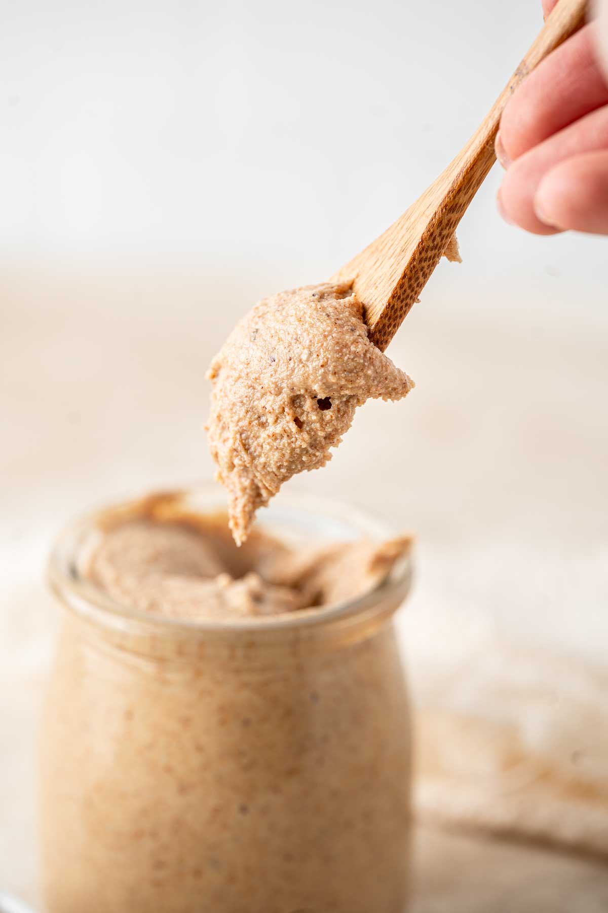 Close up of a spoon of almond butter being scooped from the jar.
