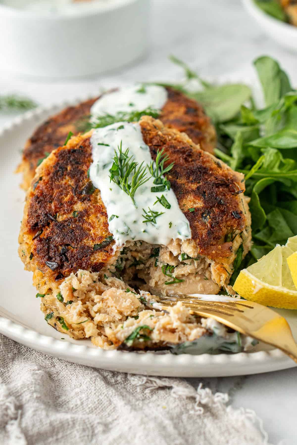 Close up of a fork breaking into one of the salmon patties.