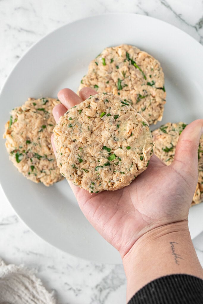 A hand shaping the mixture into 4 salmon patties.