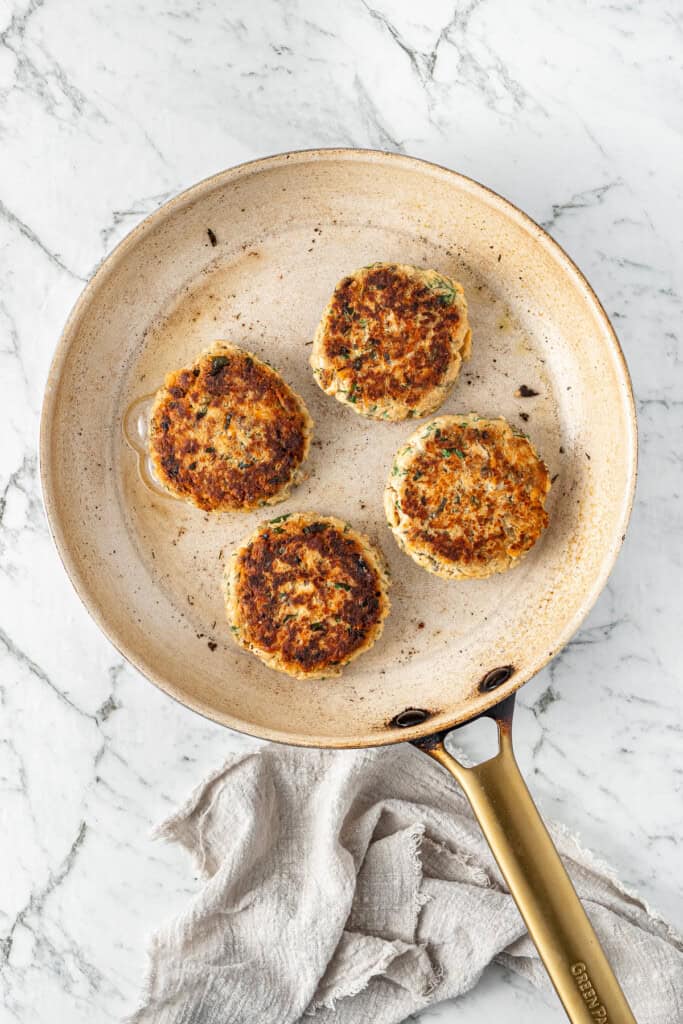 Frying the salmon patties until golden in a frying pan.