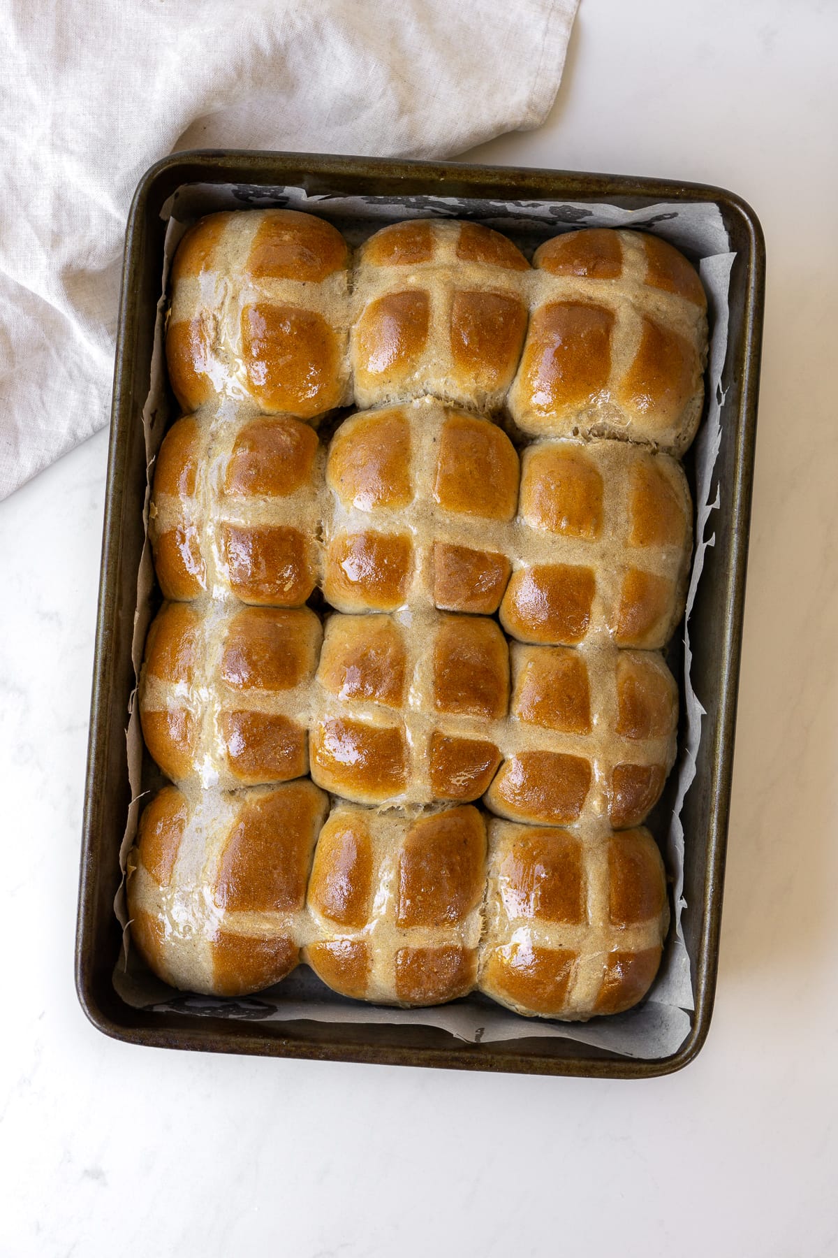 Fresh baked hot crossed buns in a baking tray.