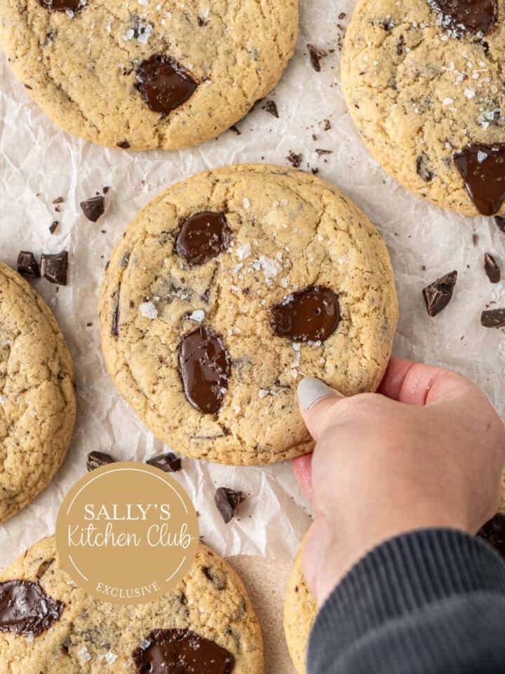 A hand picking up a giant dairy free chocolate chip cookie.