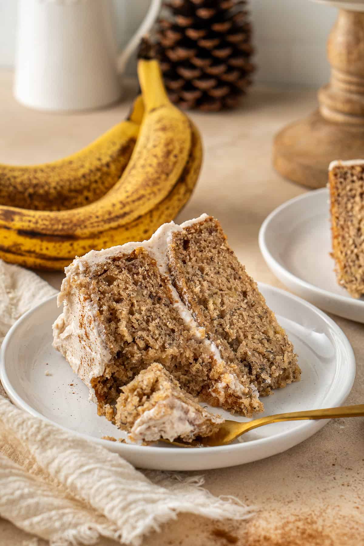 A slice of vegan banana cake on a plate with a fork taking a bite.