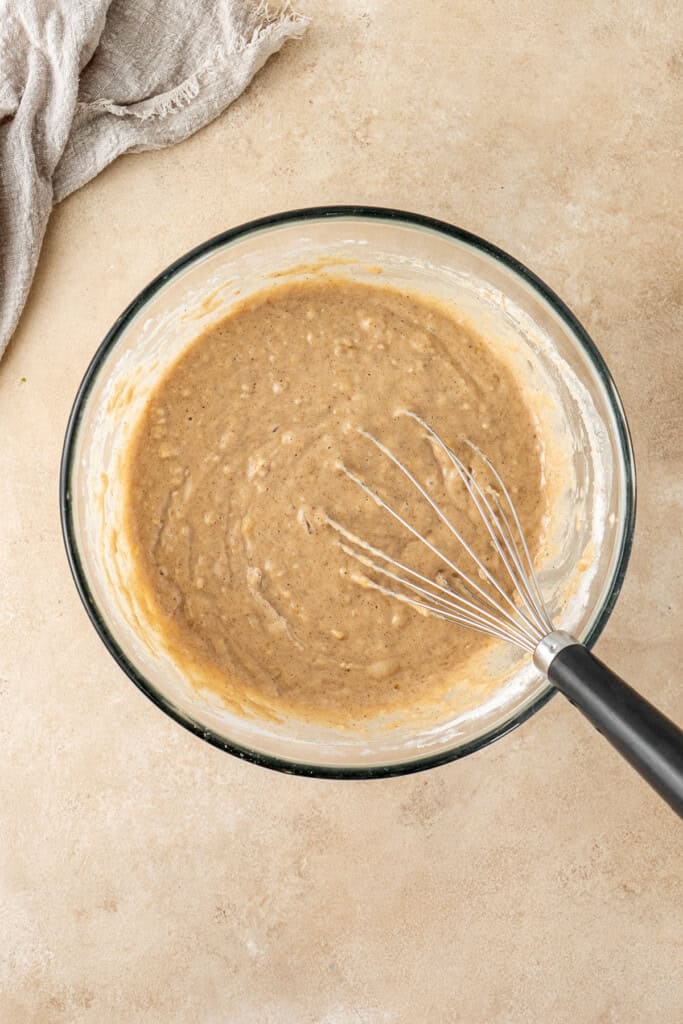 The cake batter and a whisk in a glass bowl.