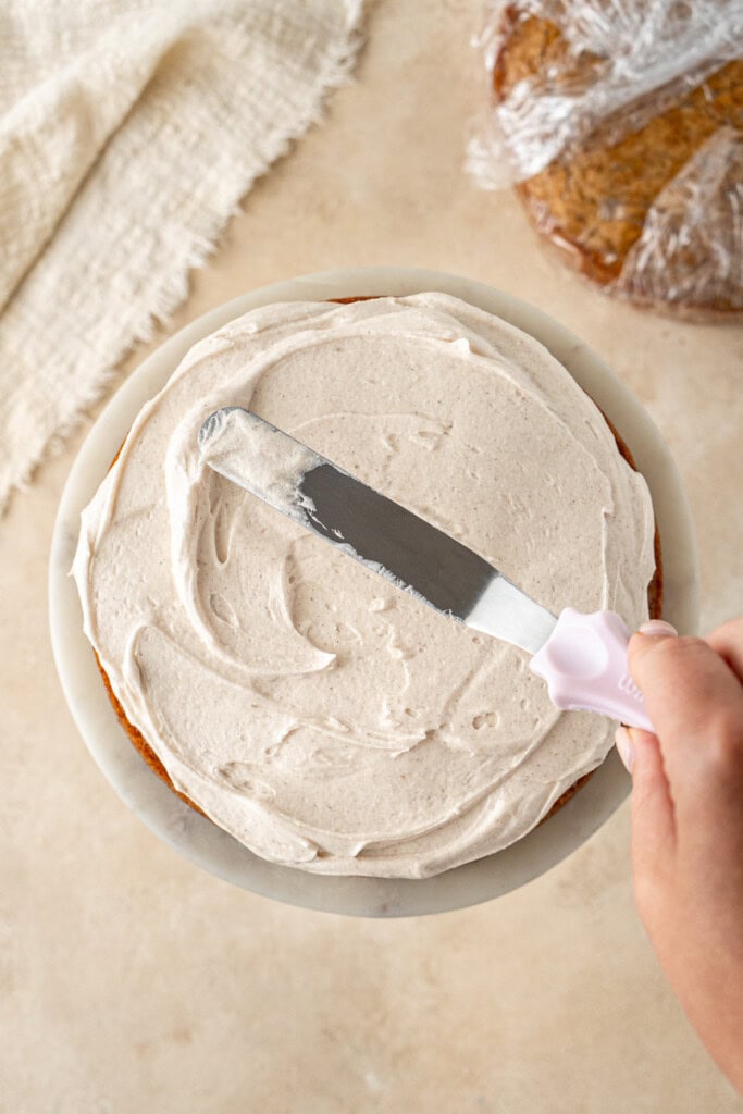 Spreading buttercream onto the cake with a cake knife.