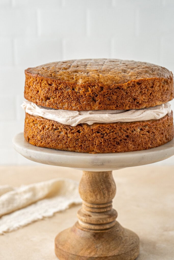 The cake layered with buttercream on a cake stand.