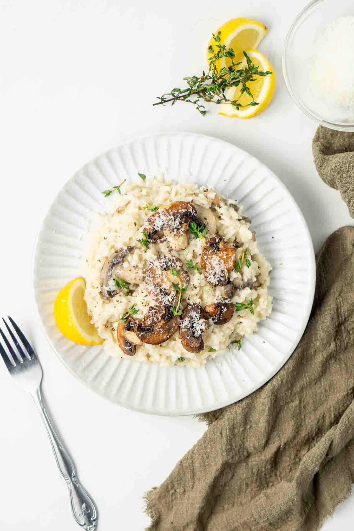 Easy pressure cooker risotto on a white plate with a green serviette and lemon slices. 