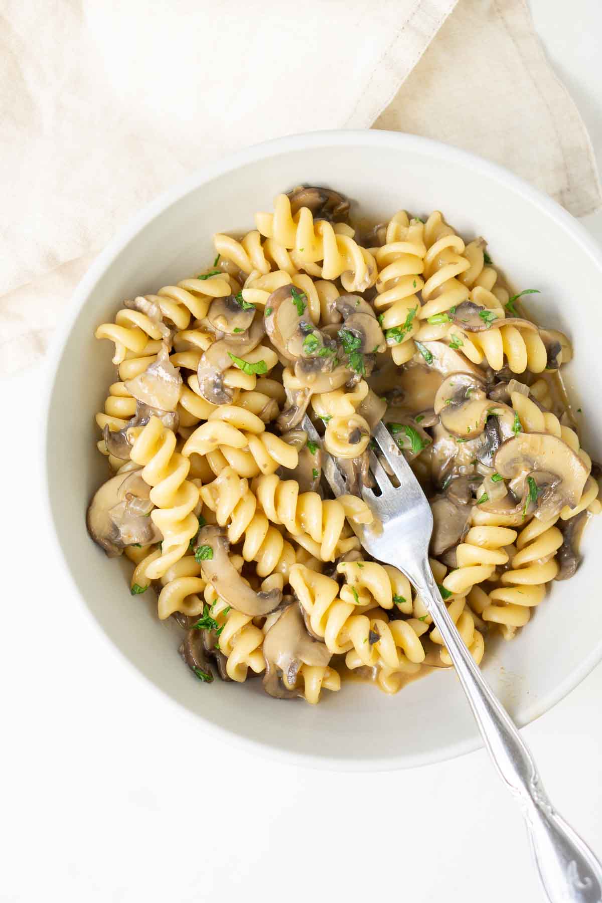 Mushroom stroganoff in a white bowl with a fork.
