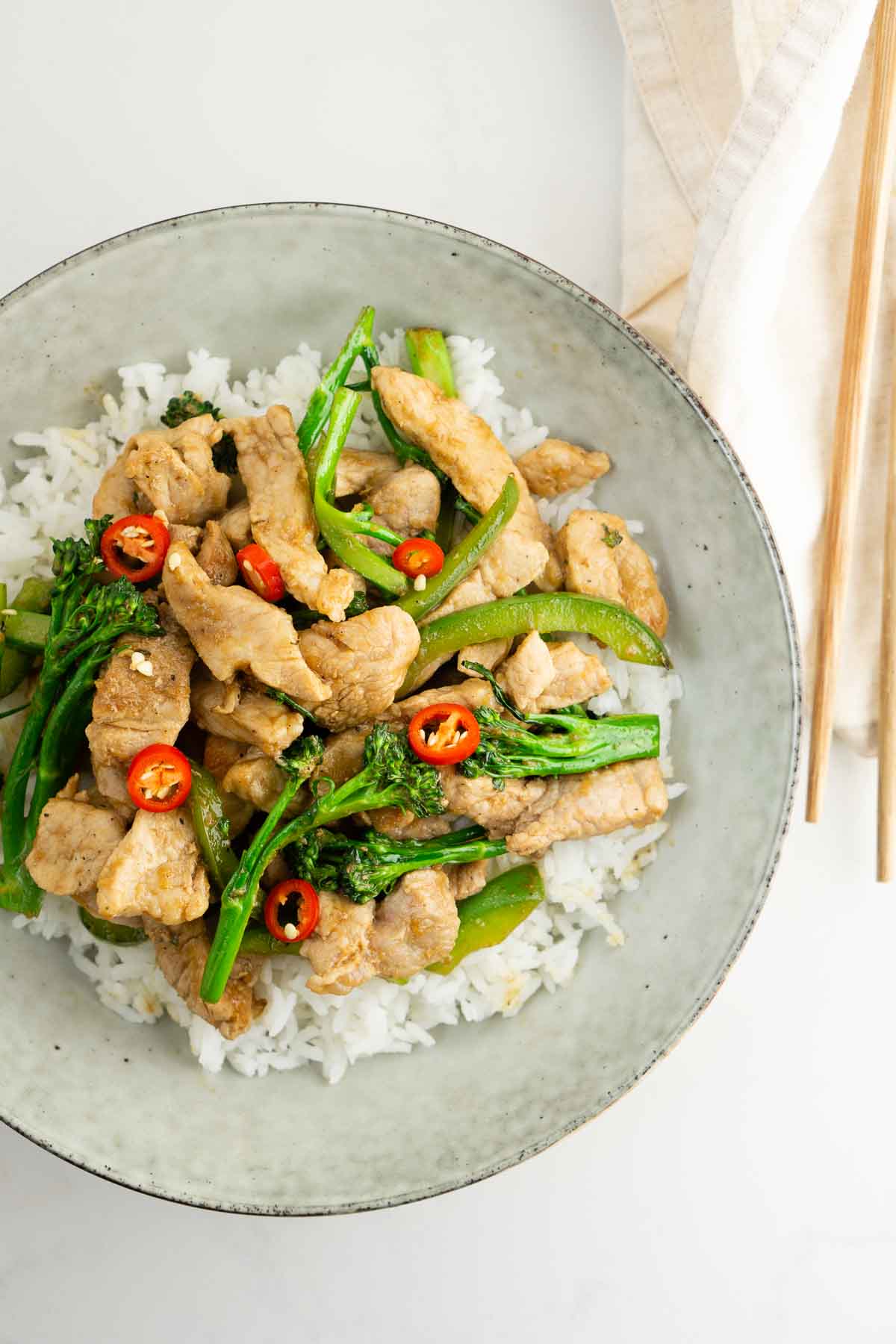Pork stir fry served in a bowl with white rice and fresh chilli 