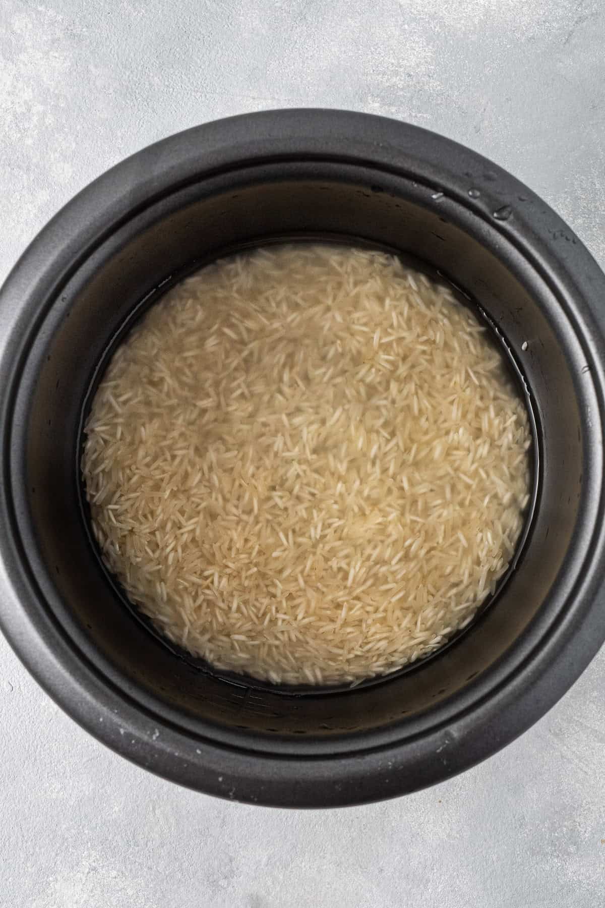 The rice being washed in the rice cooker.
