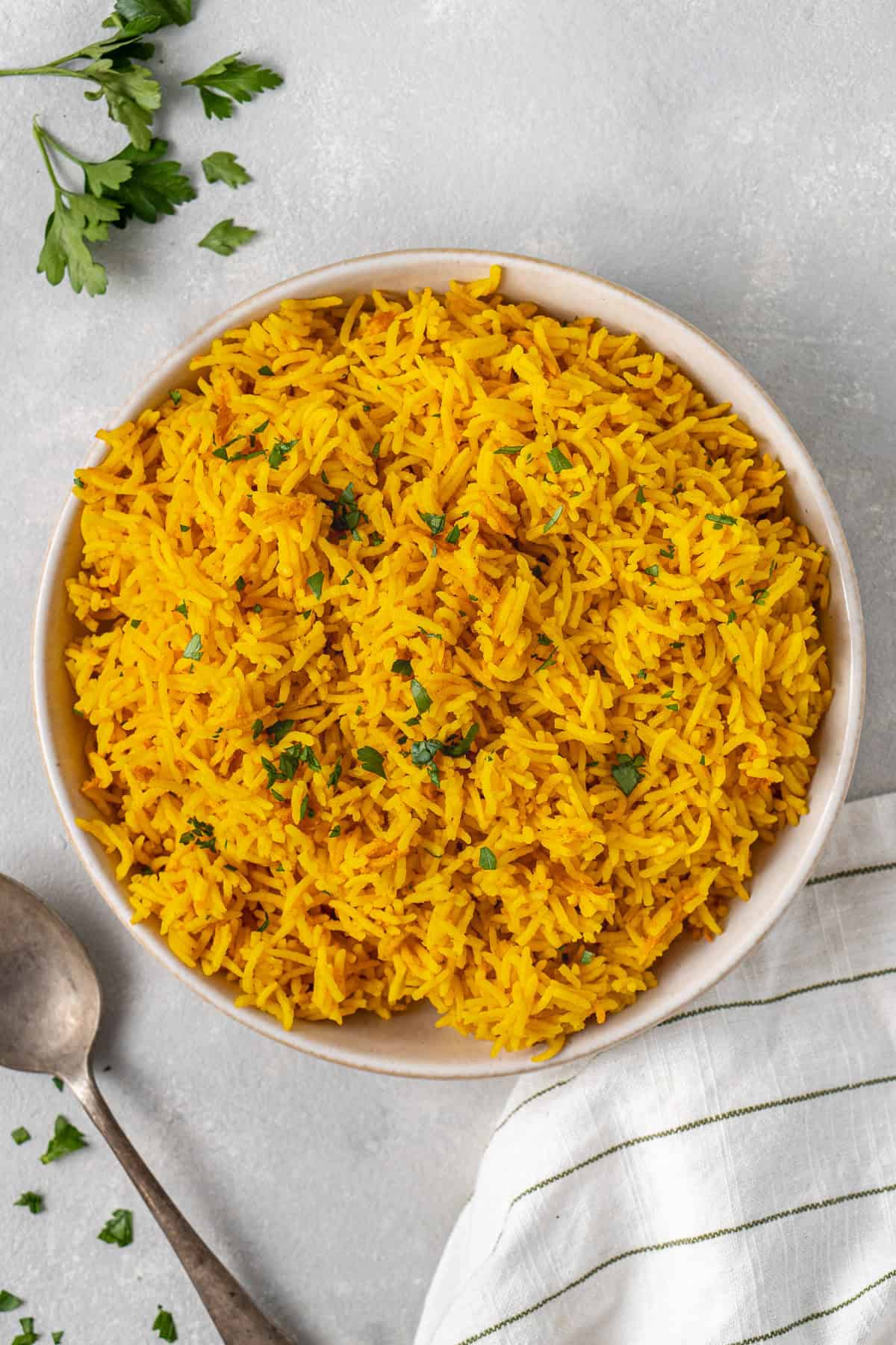 A bowl of yellow rice on a grey background.