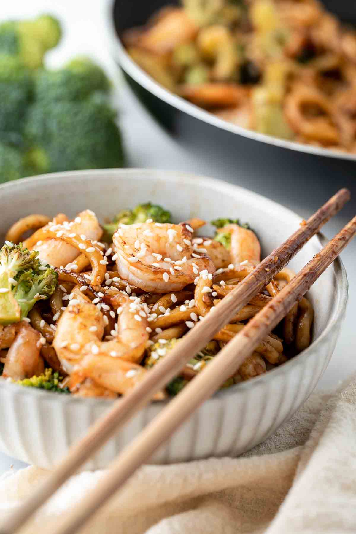 Garlic prawn noodles in a white bowl with chopsticks.