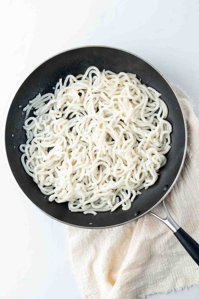 Udon noodles in a pan.