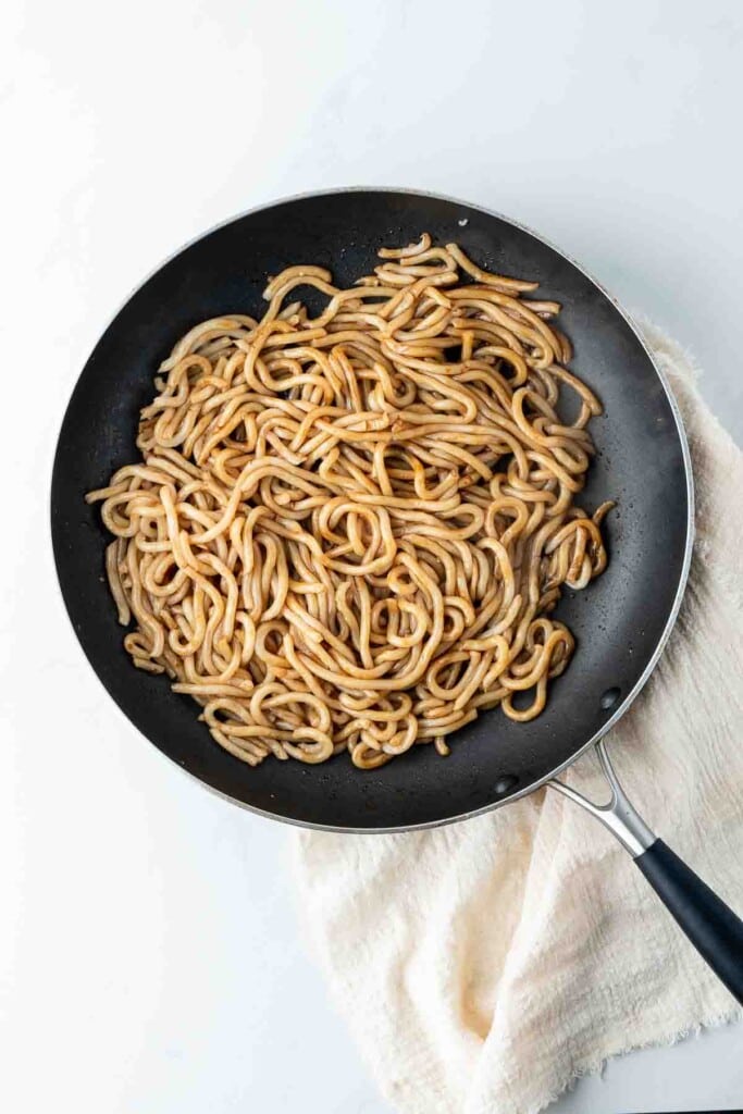 Udon noodles and sauce in a pan.