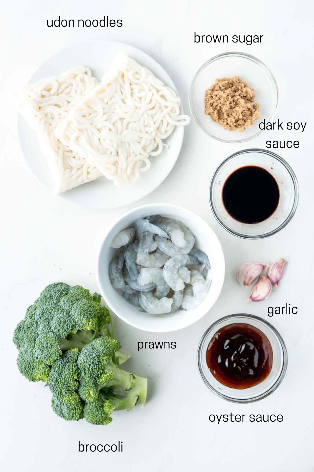 All ingredients needed to make garlic prawn noodles laid out in bowls.