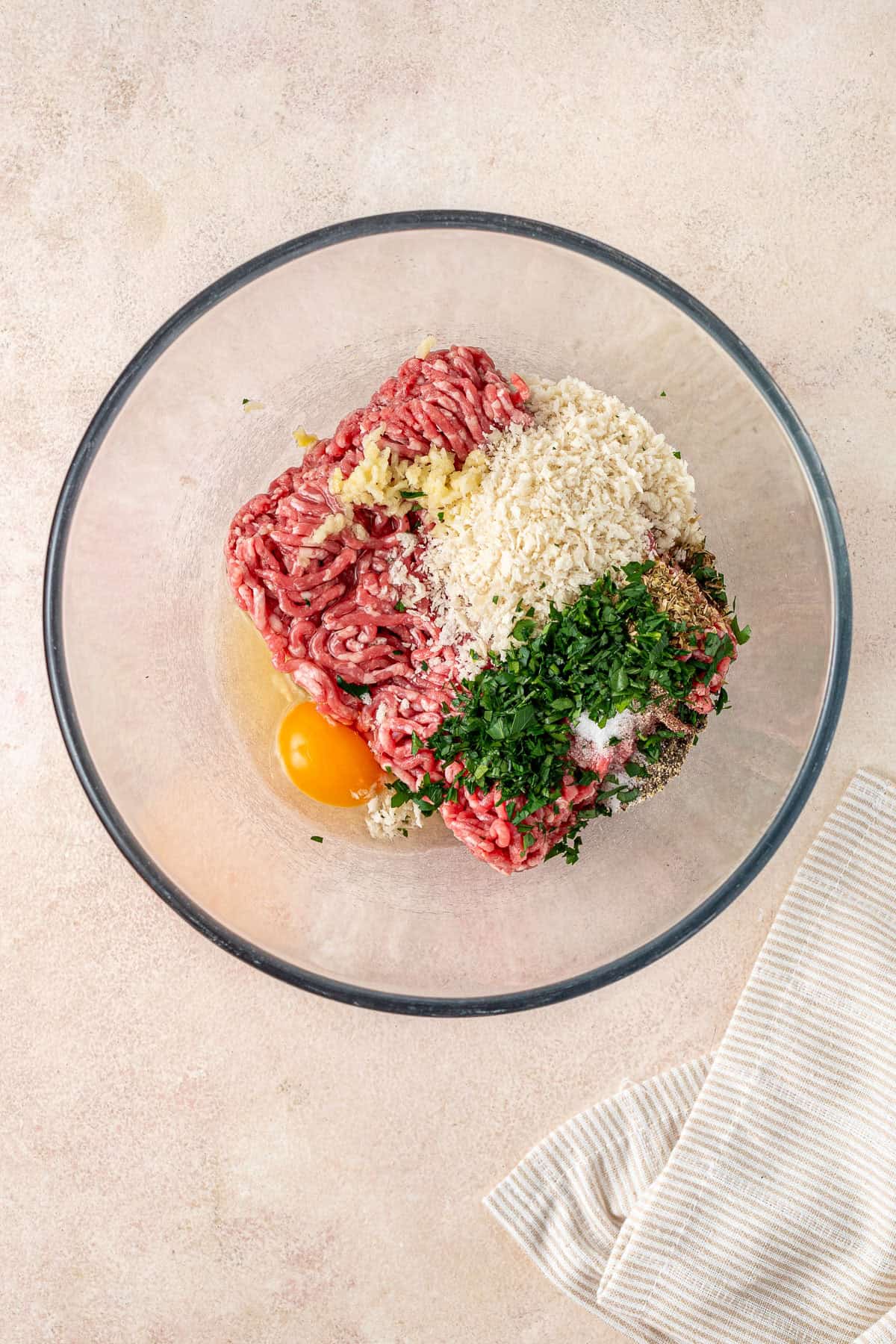 All ingredients for beef meatballs in a glass bowl.