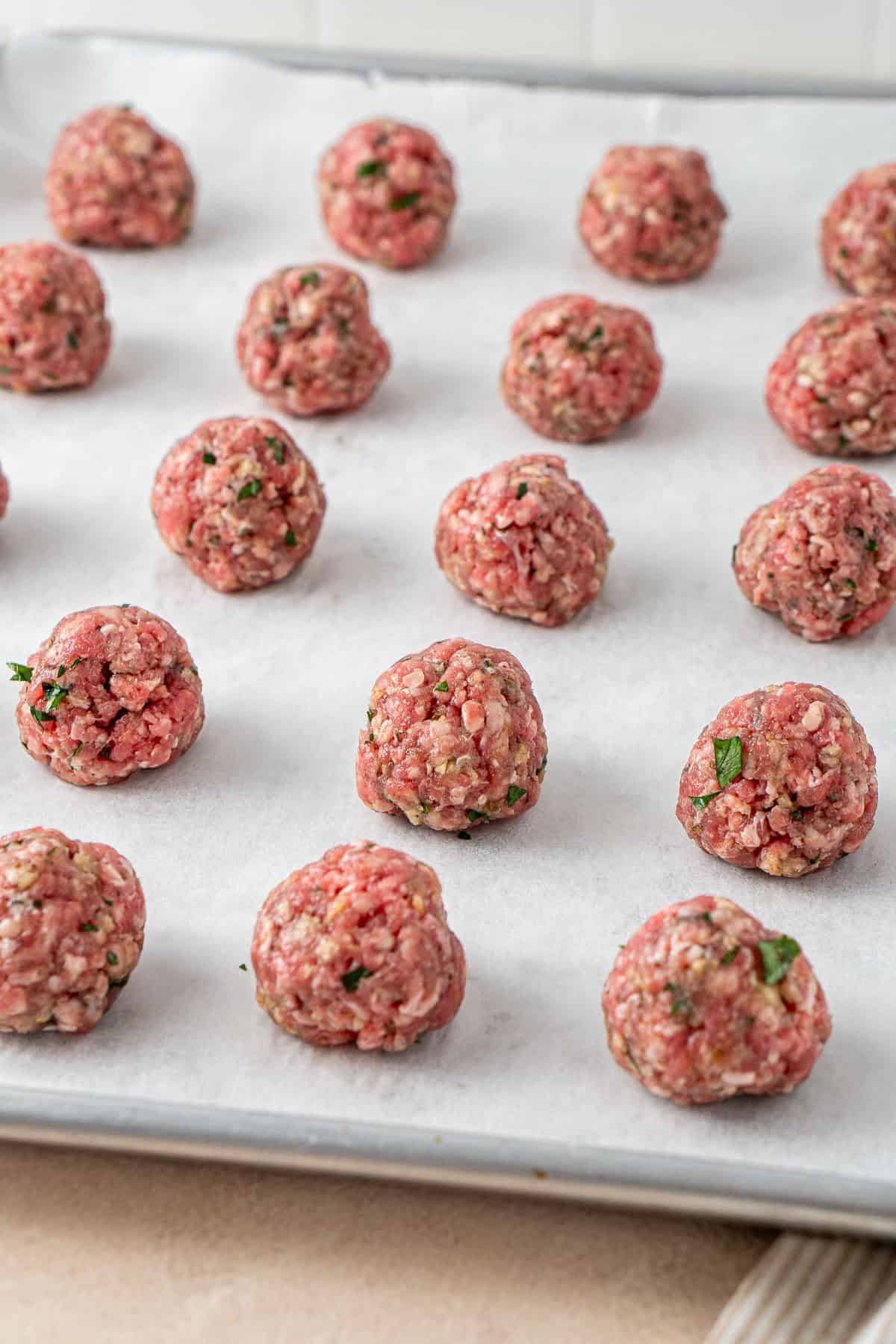 The beef meatballs rolled into balls on a baking tray.