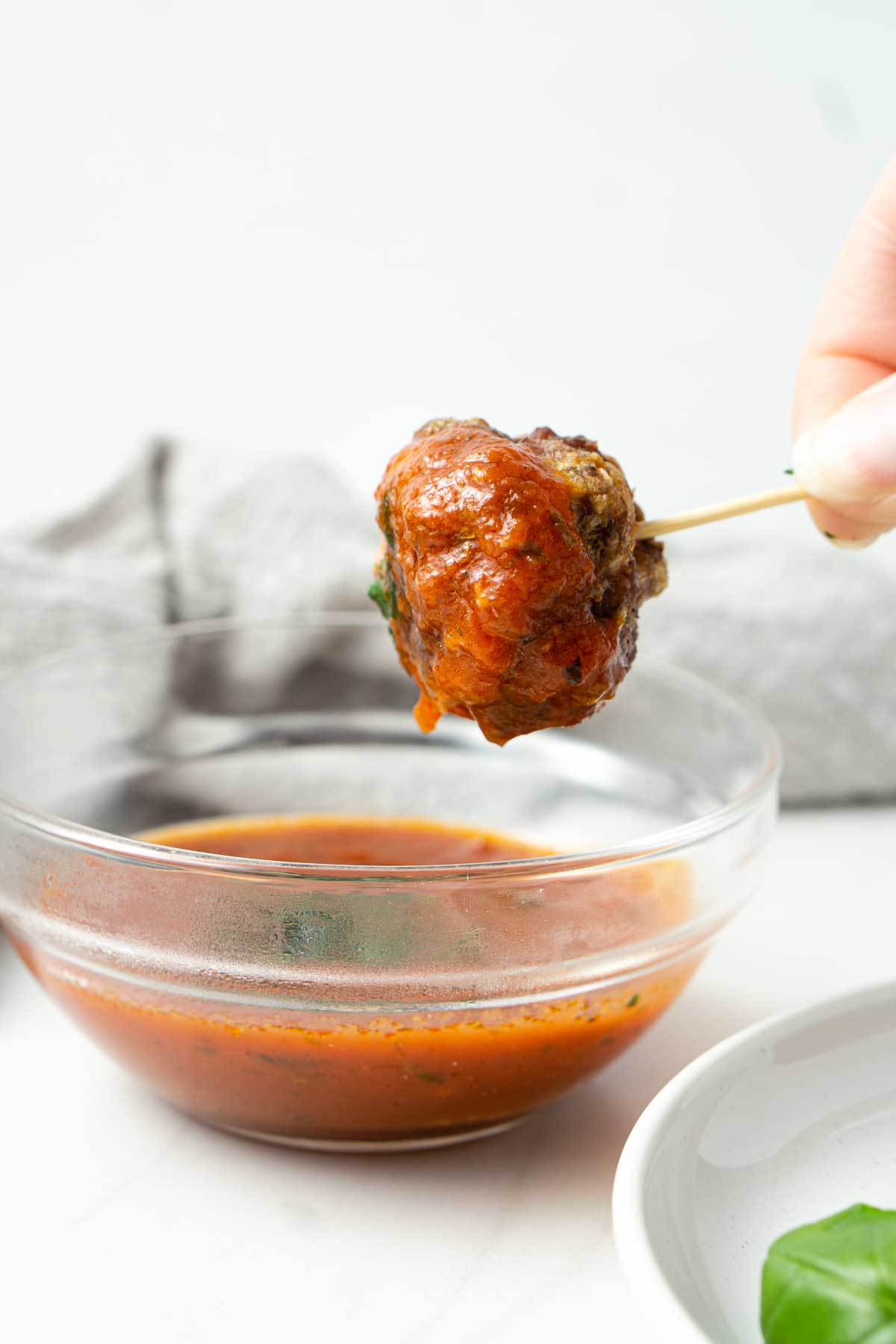 Meatball being dunked into tomato sauce