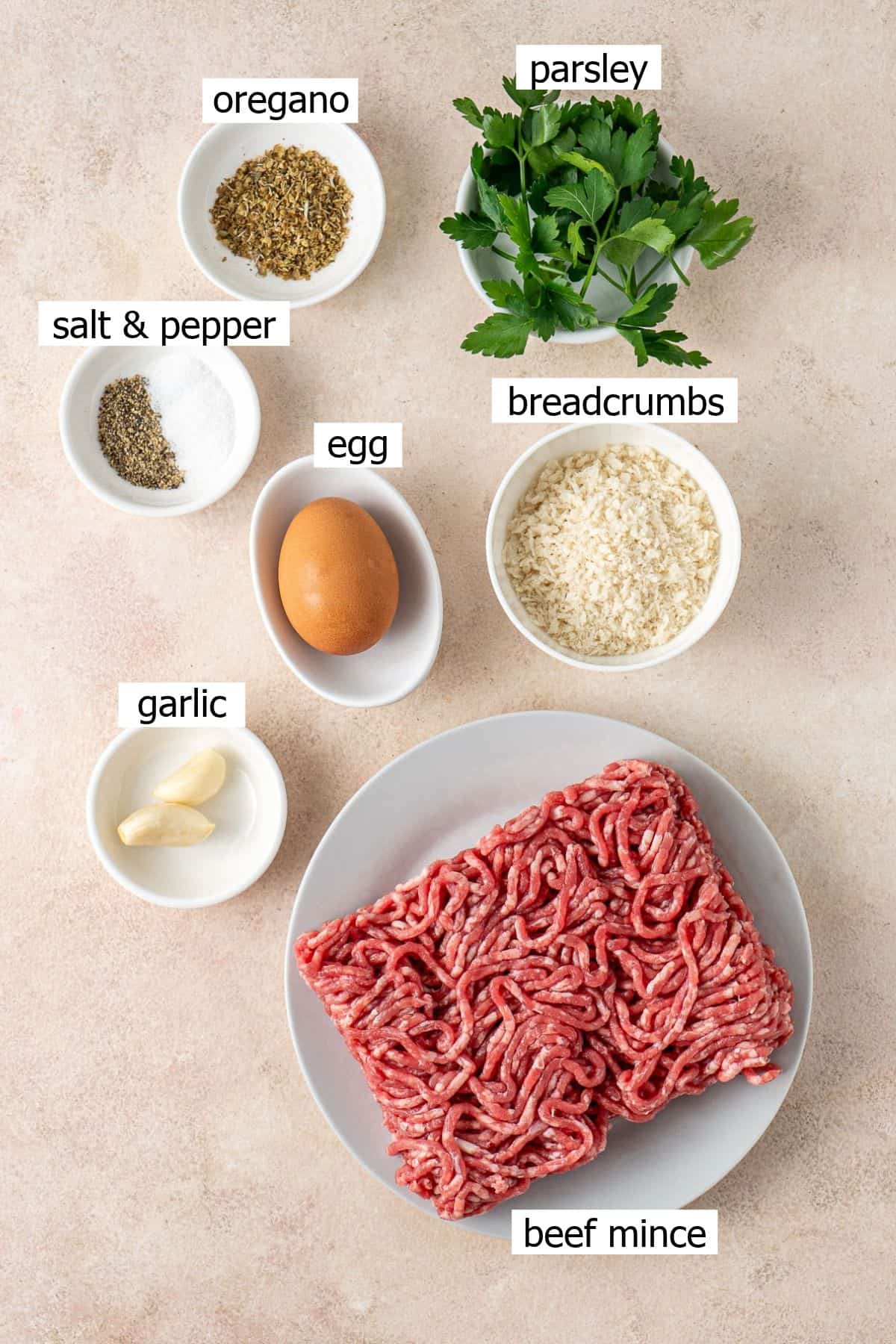 All ingredients needed to make baked beef meatballs laid out in bowls.