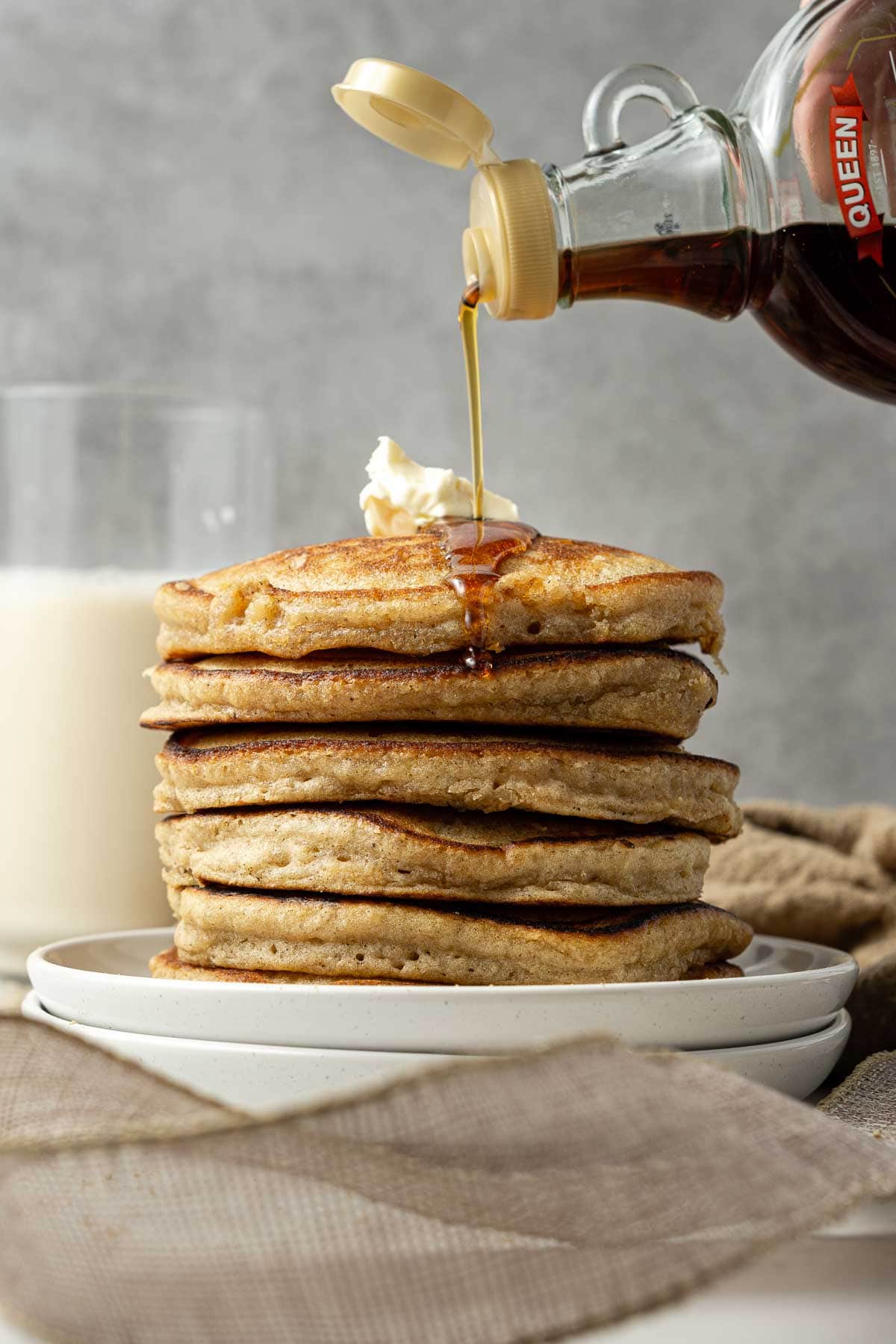 Stack of gingerbread pancakes on a plate with a drizzle of maple syrup and butter.