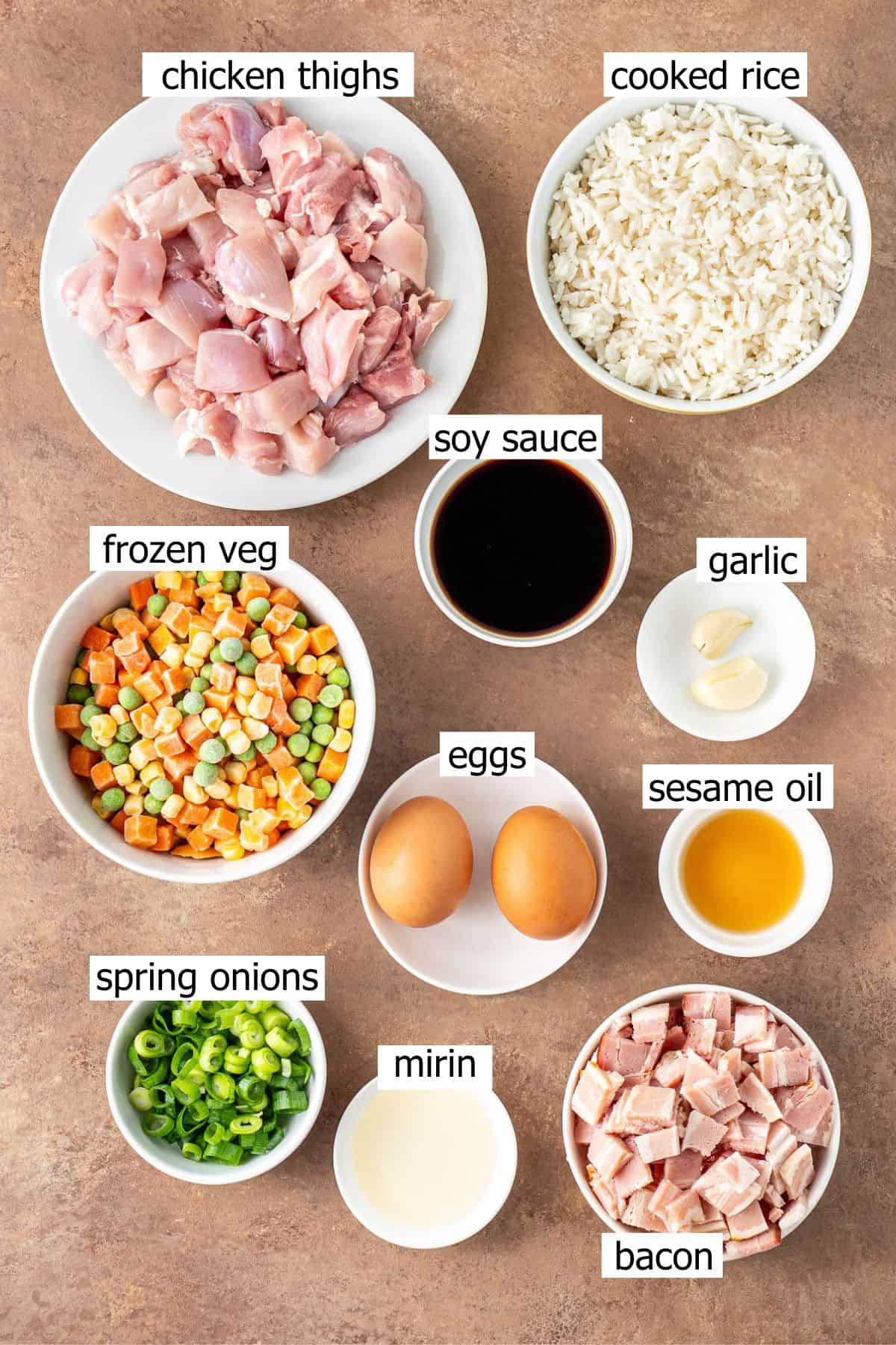 All ingredients needed to make chicken fried rice laid out in bowls.