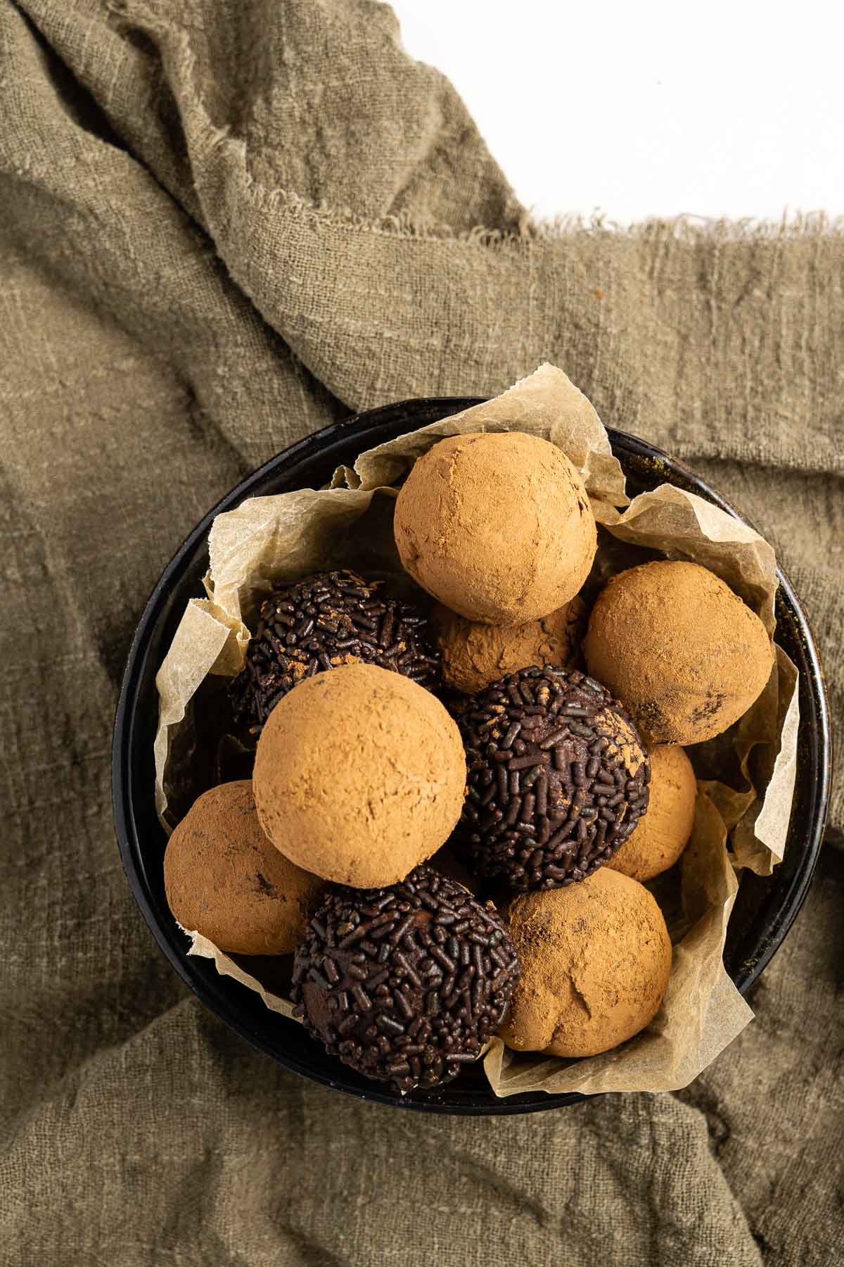 chocolate ganache truffles in a bowl with cocoa powder and chocolate sprinkles