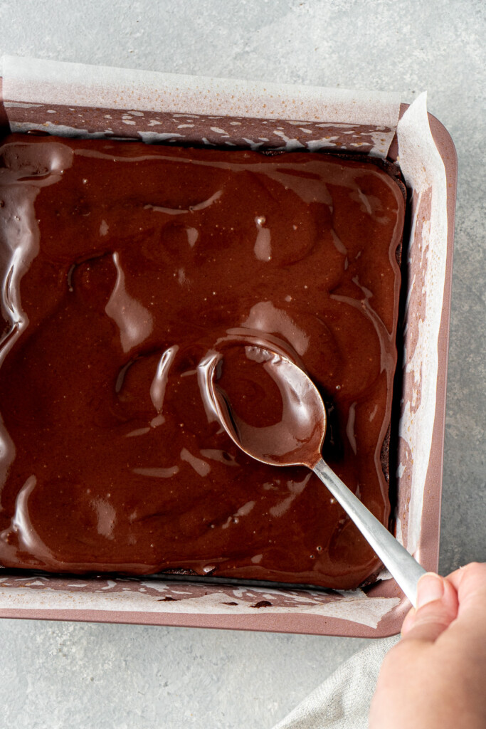 Spreading the ganache over the top of the brownies.