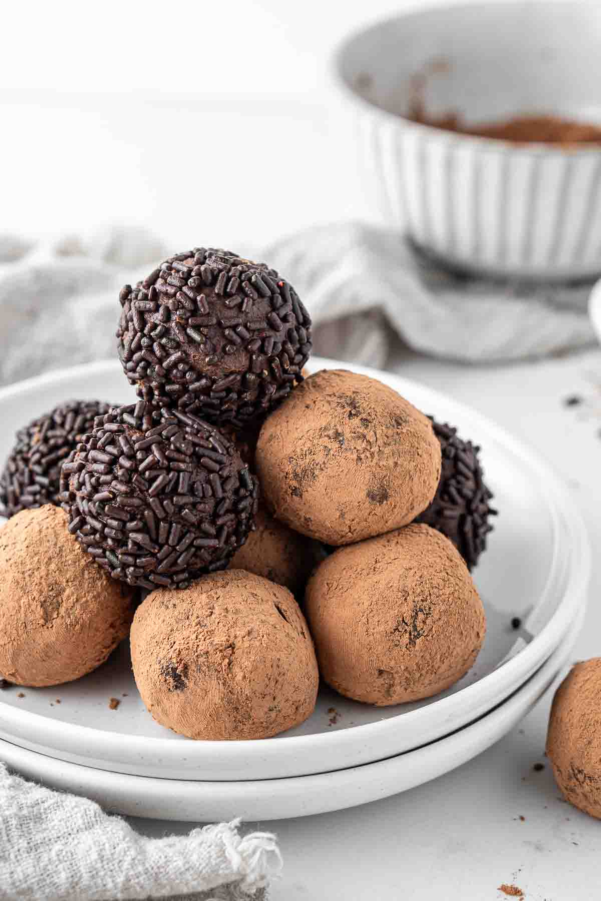Vegan chocolate truffles on a plate coated in chocolate sprinkles and cocoa powder. 