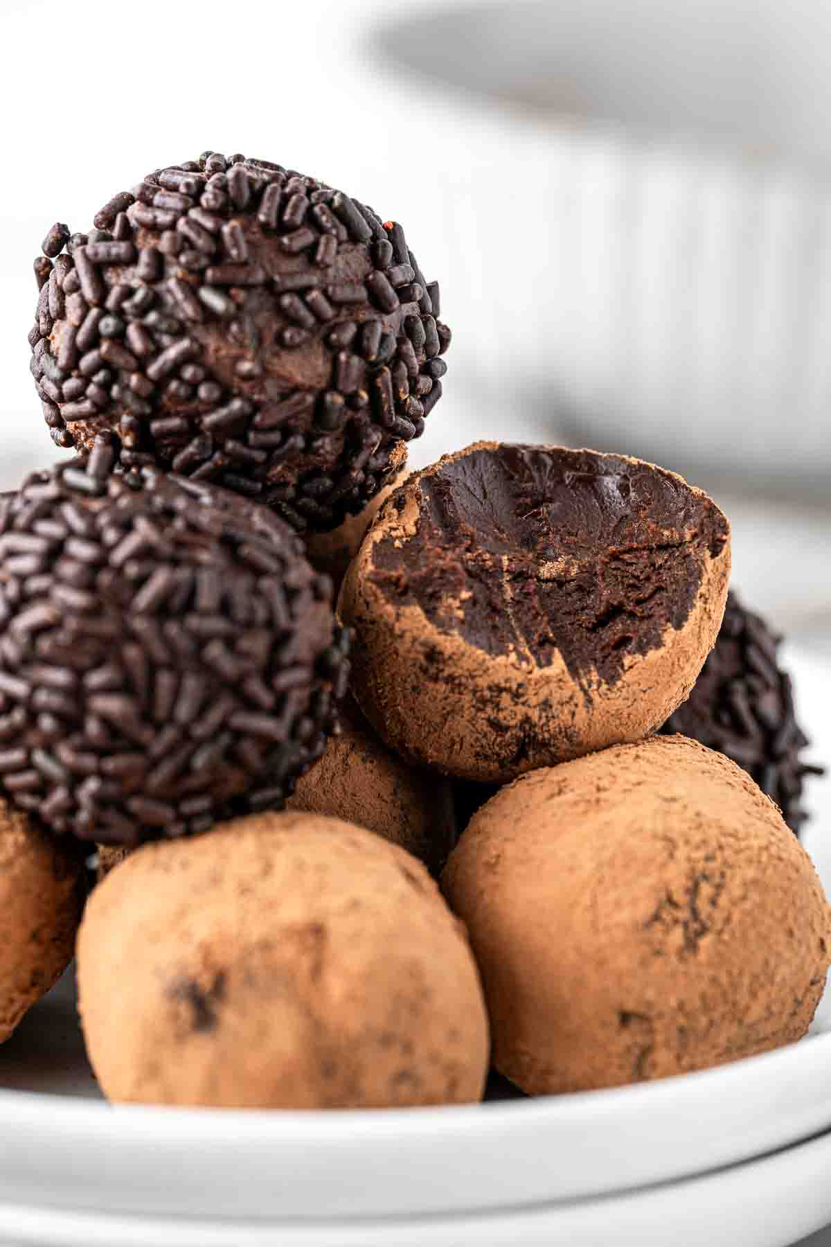 Close up of vegan chocolate truffles on a plate with a bite taken. 