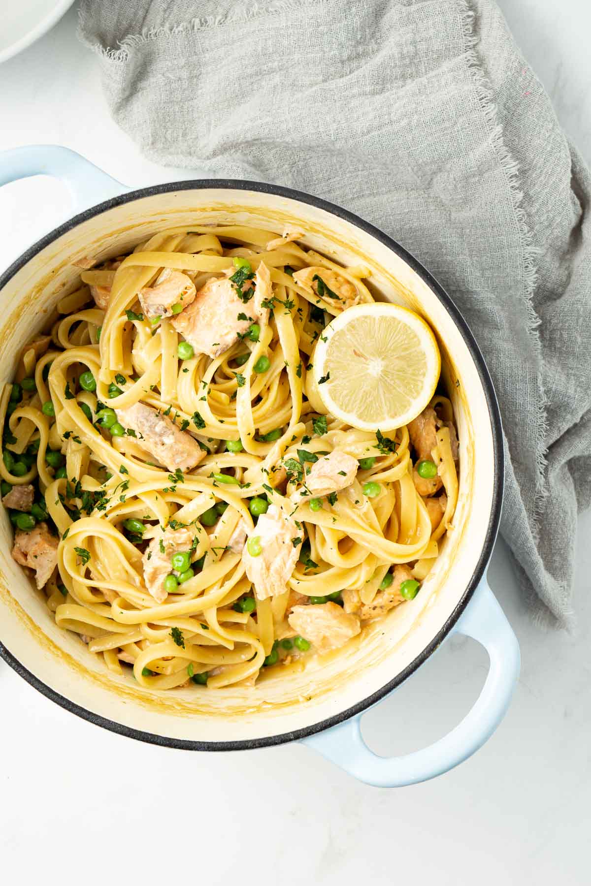 Creamy salmon pasta in the pot with lemon and parsley to garnish.