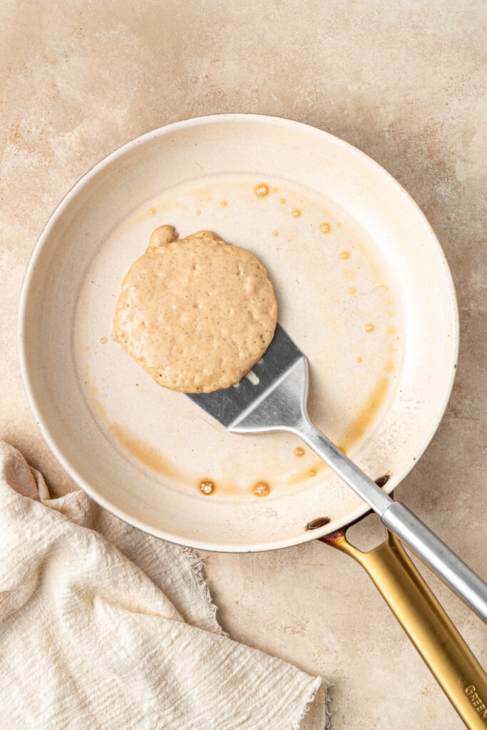 A pancake cooking in a frying pan.