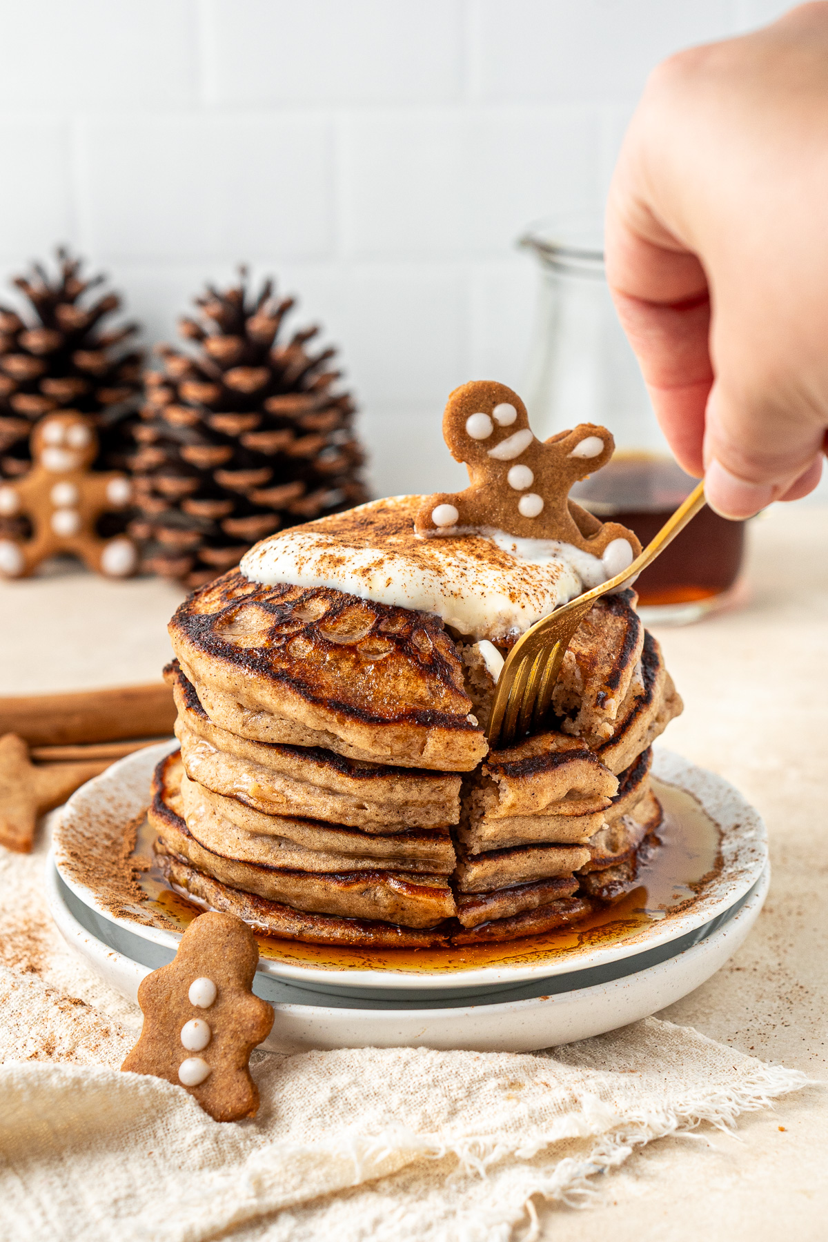 A hand using a fork to take a bite of gingerbread pancakes.