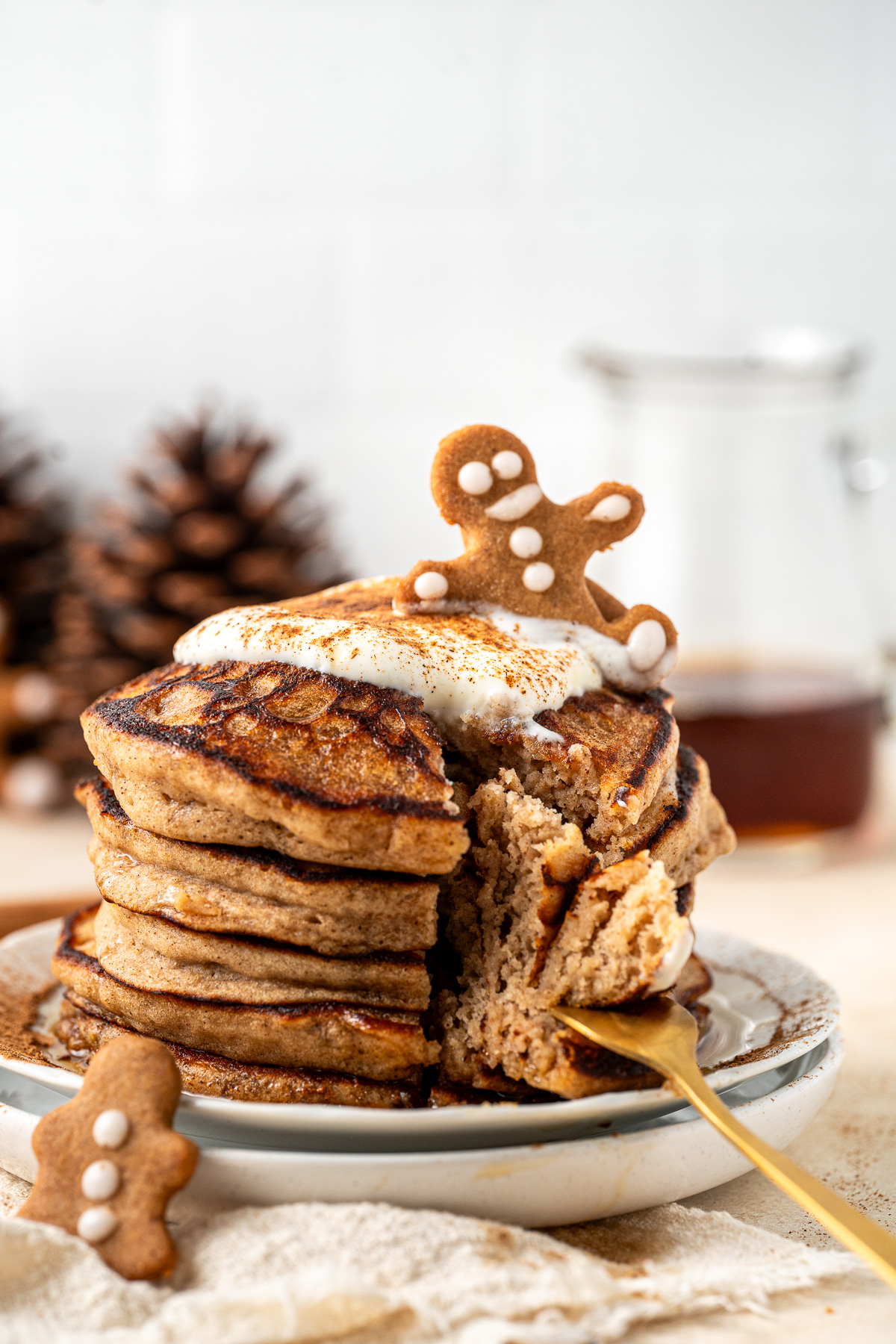 A stack of gluten free gingerbread pancakes with yoghurt and a fork taking a bite.