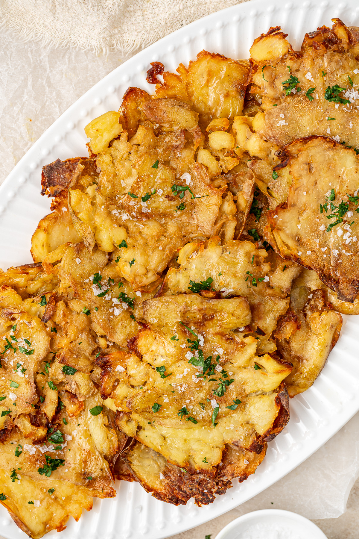 Salt and vinegar smashed potatoes on a serving plate.