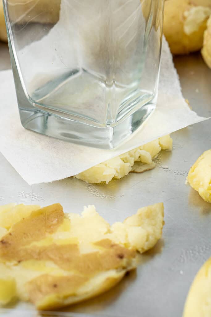 Using a glass to smash the potatoes.