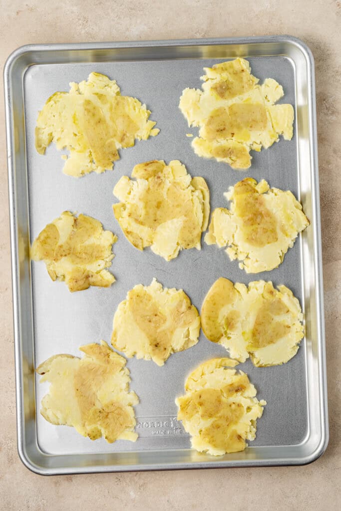 Smashed potatoes on a baking tray.