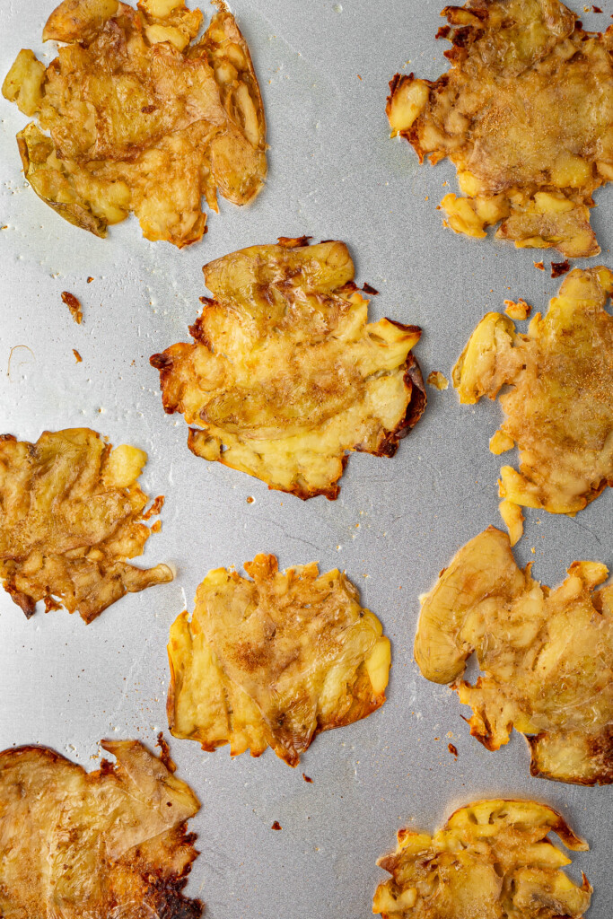 Crispy smashed potatoes on a baking tray.