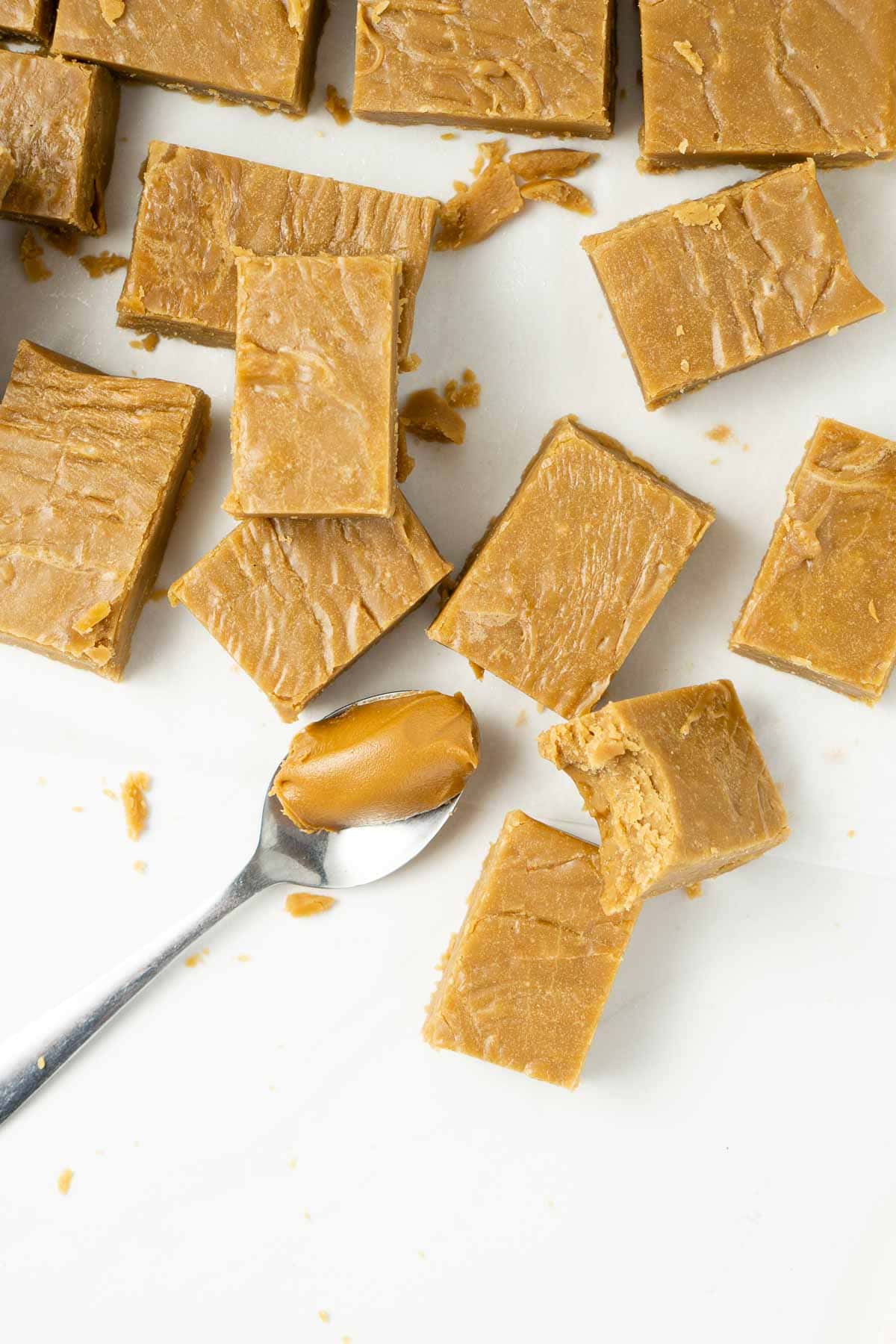 squares of vegan biscoff fudge with a spoonful of bsicoff spread