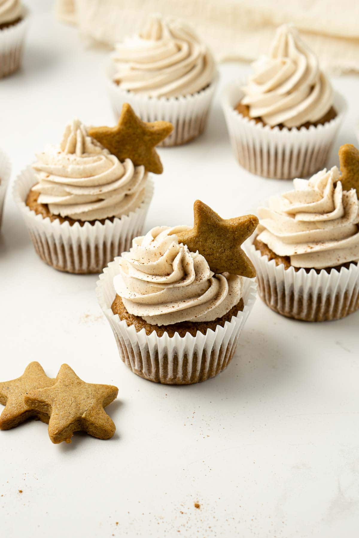 Group of vegan gingerbread cupcakes with cinnamon buttercream and mini gingerbread cookies.