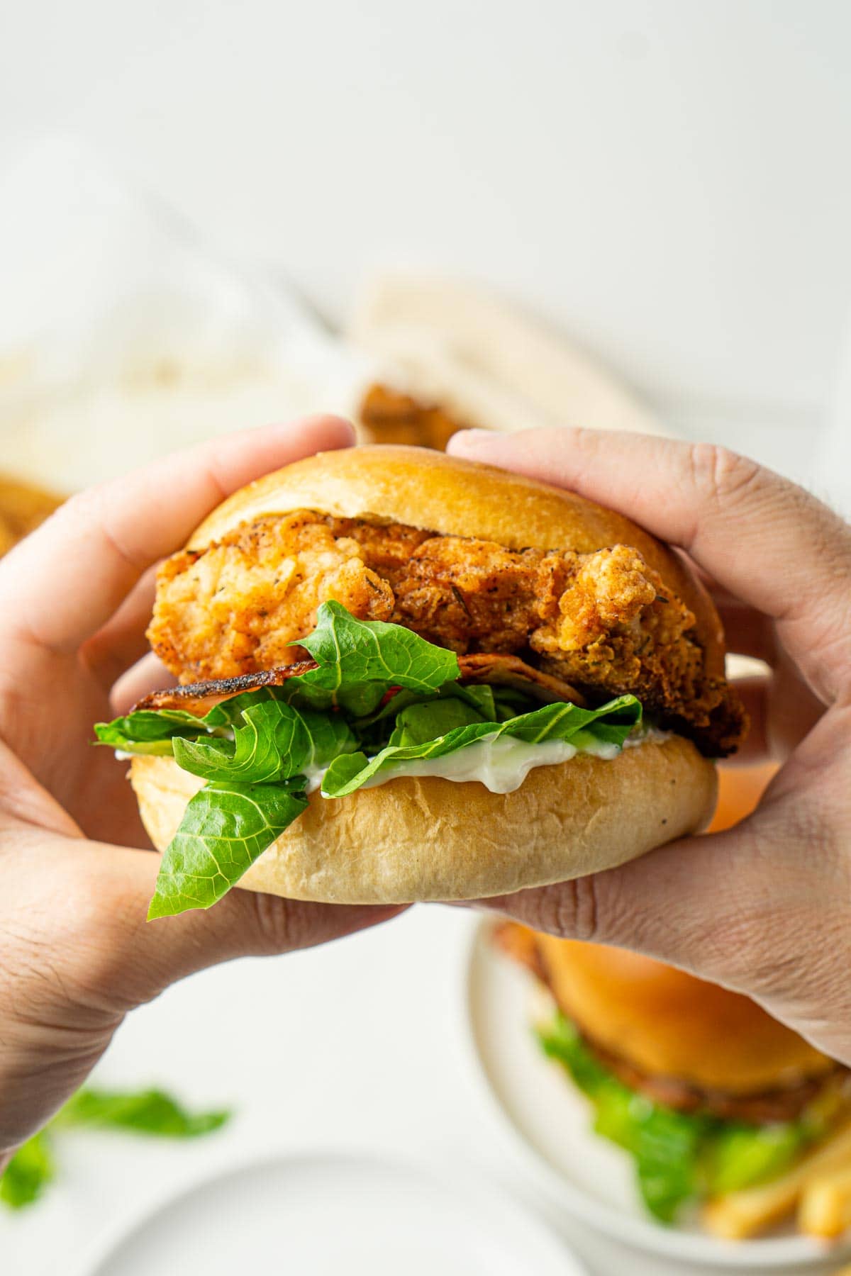 Crispy chicken burger being held by two hands.