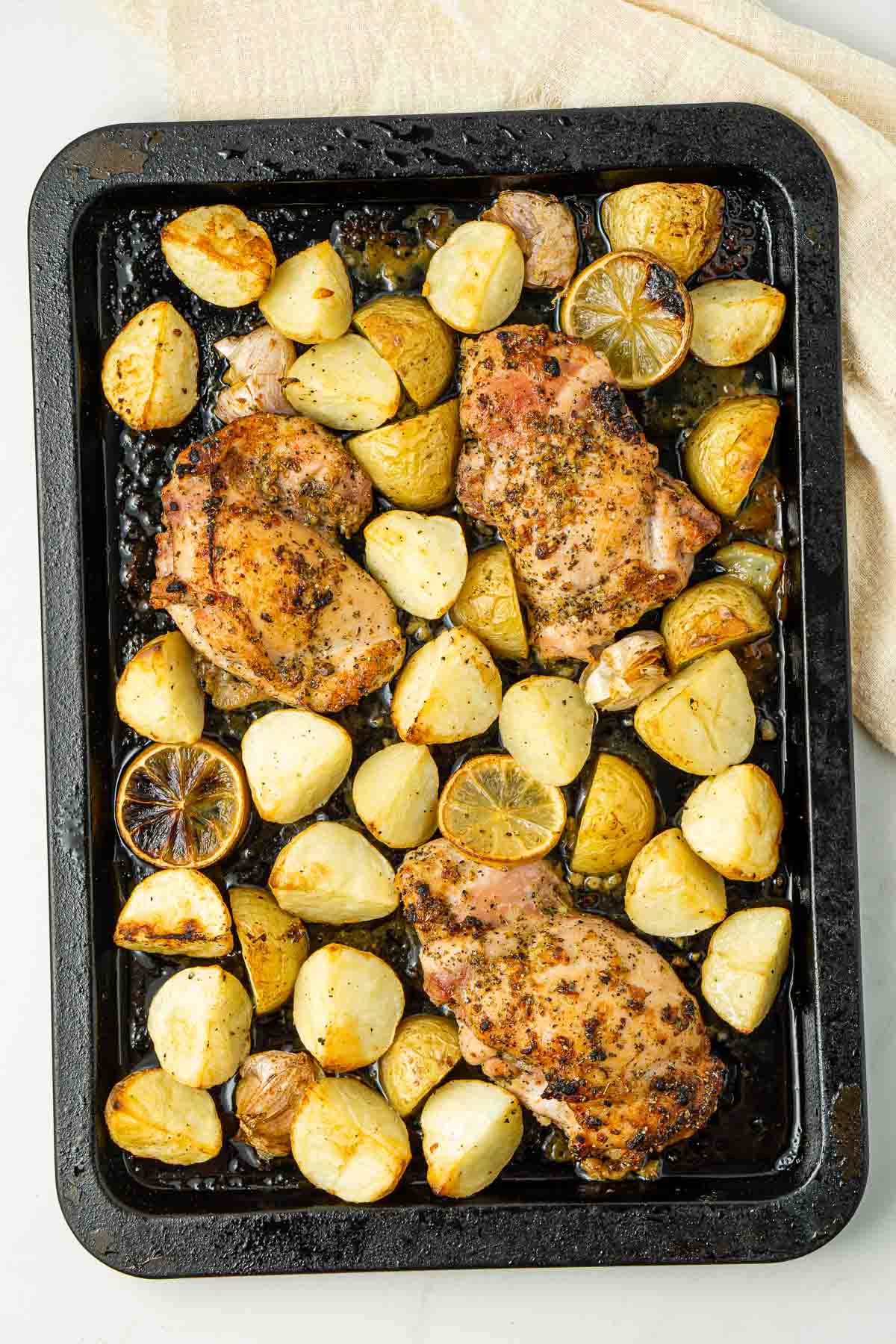 Roasted chicken, potato and lemon on a baking tray.
