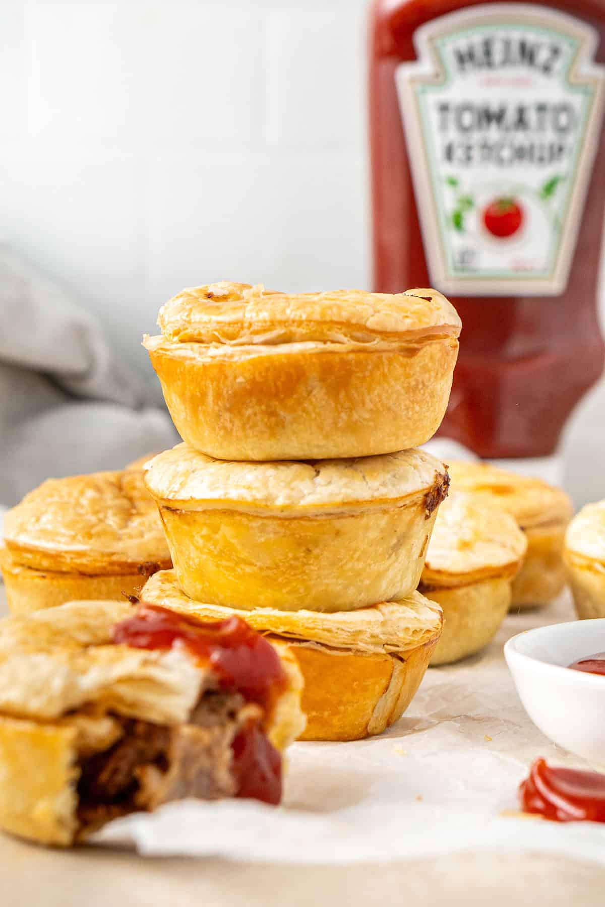 A stack of three party pies with ketchup.