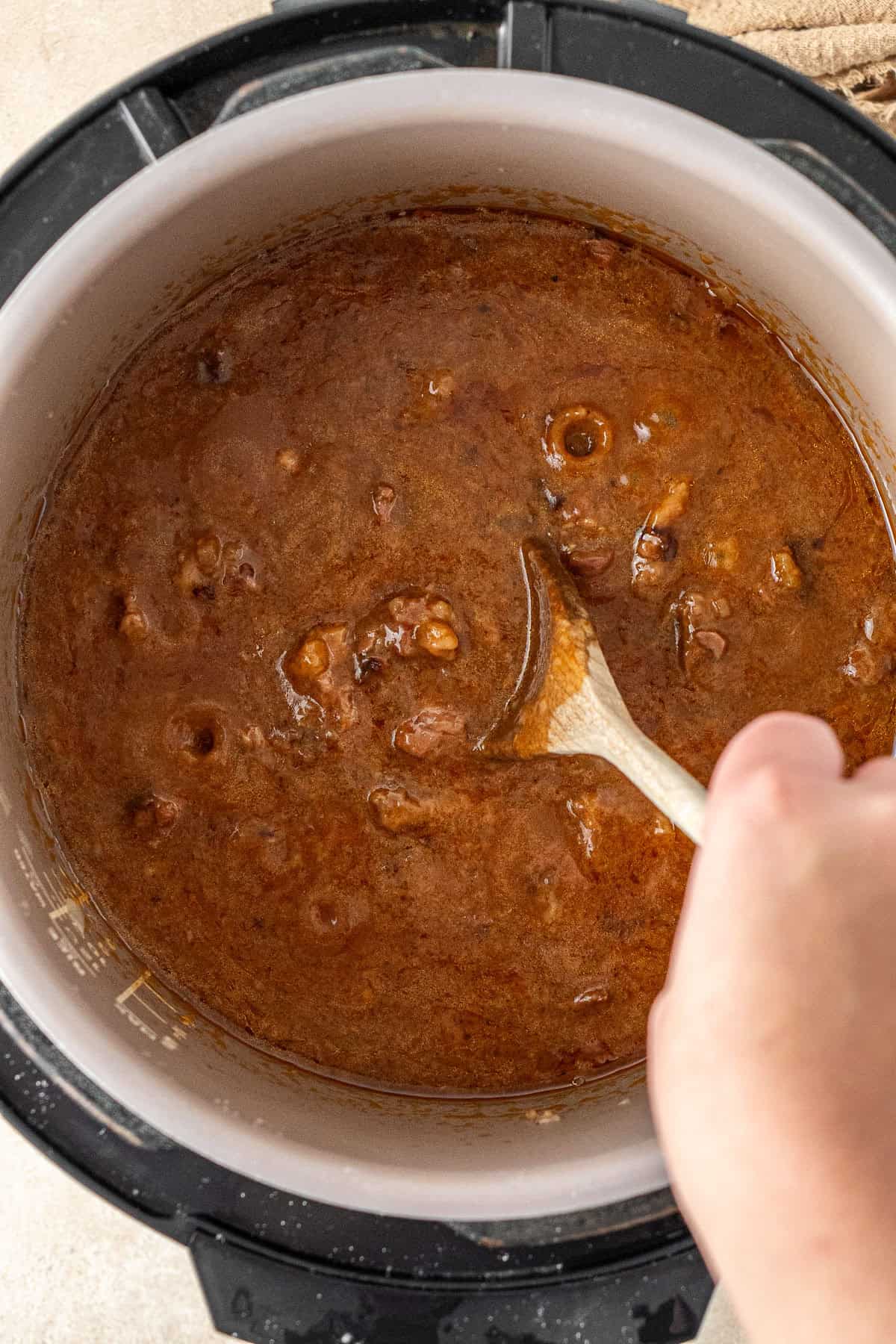 Mixing the cooked chunky steak filling with a wooden spoon.