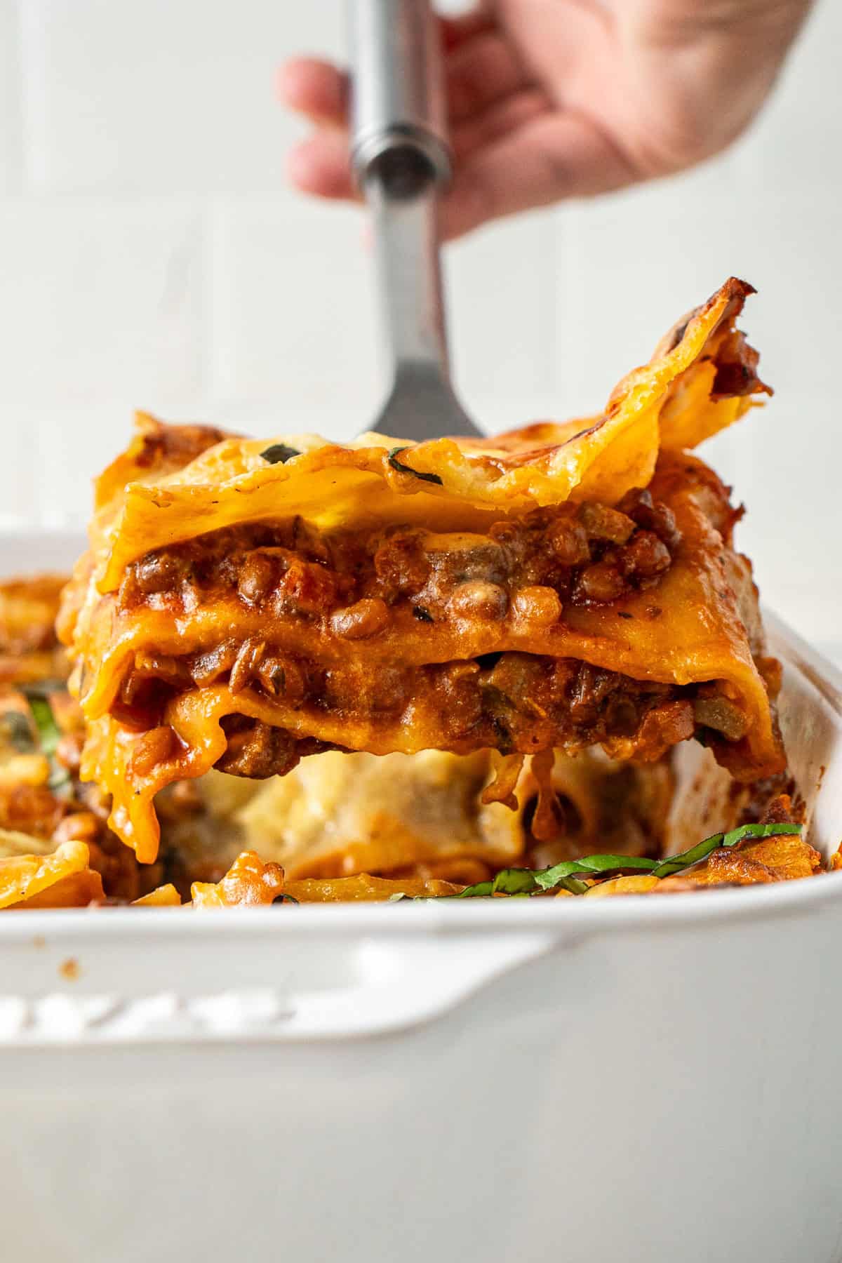 Serving a square of lentil lasagne.
