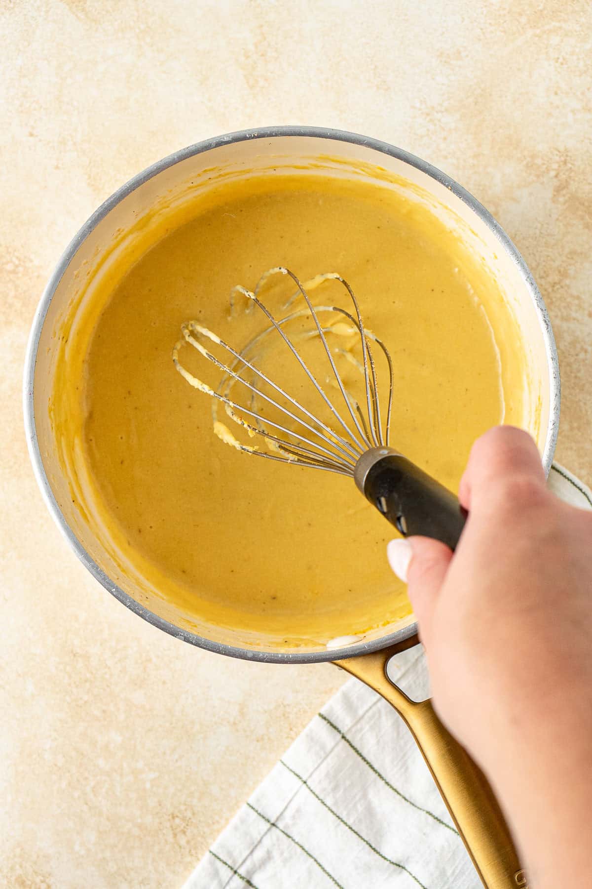 A hand whisking the dairy free bechamel sauce.