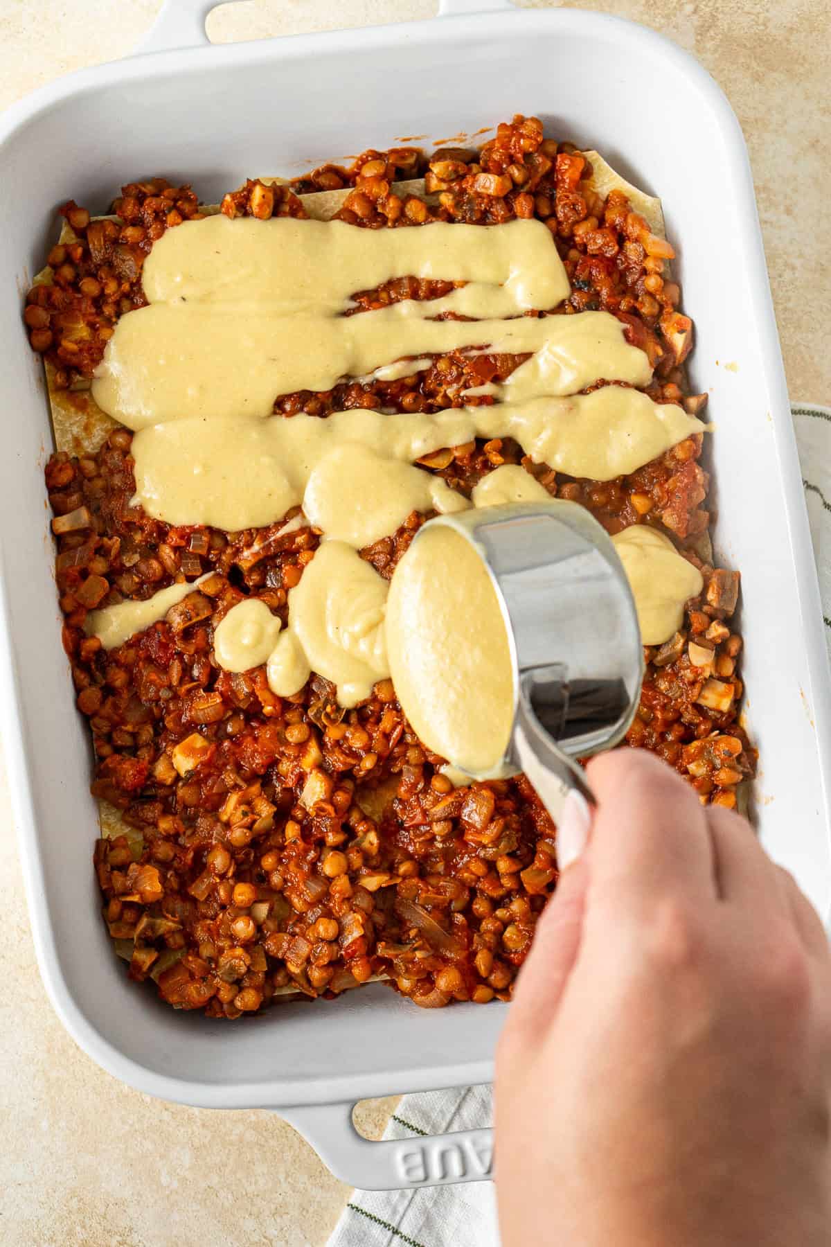 Layering the lasagne with the lentil sauce and bechamel.